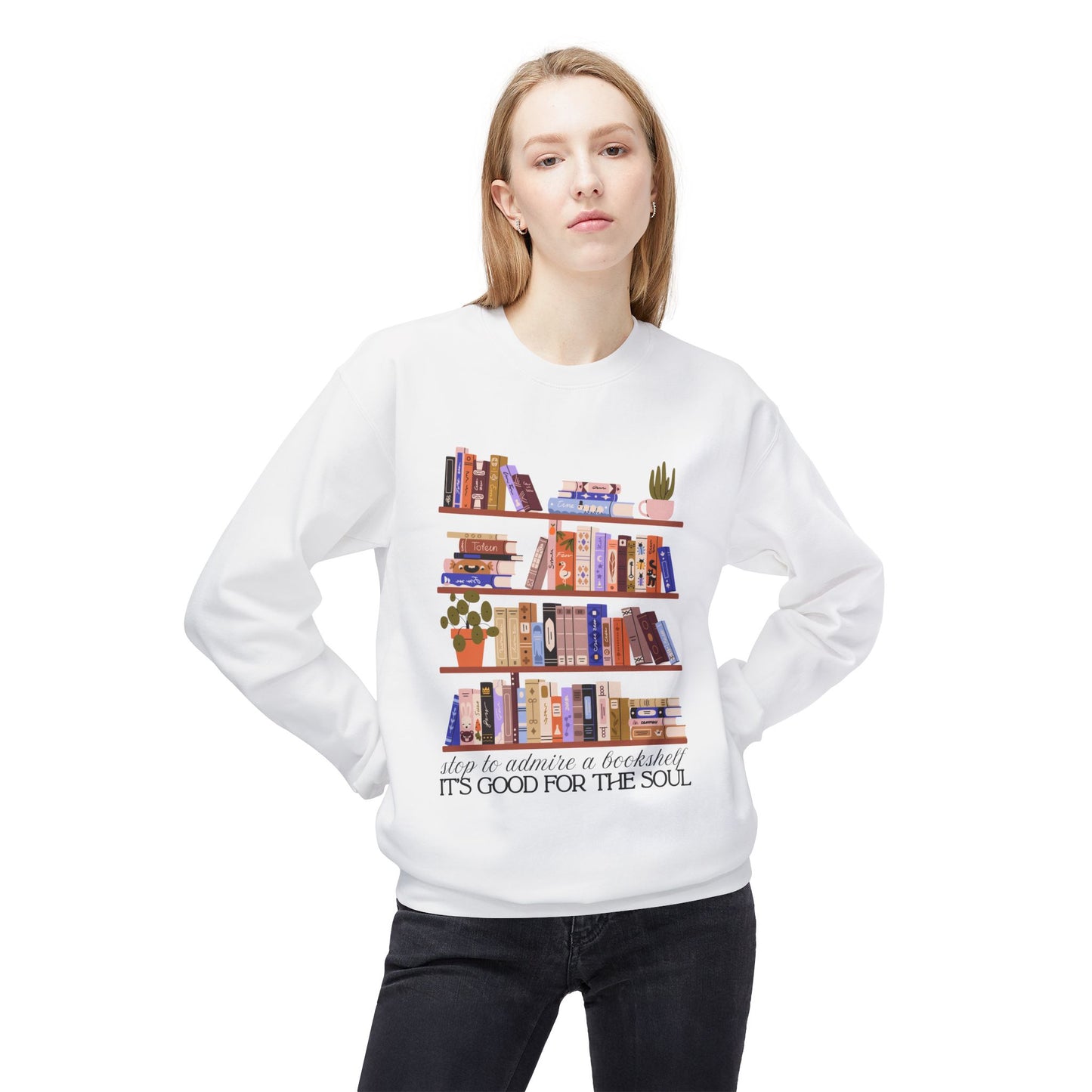 Woman wearing a white sweatshirt with bookshelf design and text 'Stop to admire a bookshelf, it's good for the soul'