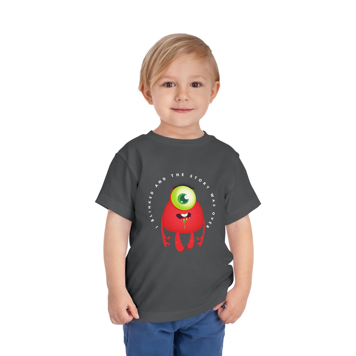 Child wearing a gray toddler t-shirt with a drooling, one eyed, red monster graphic and text 'I blinked and the story was over'