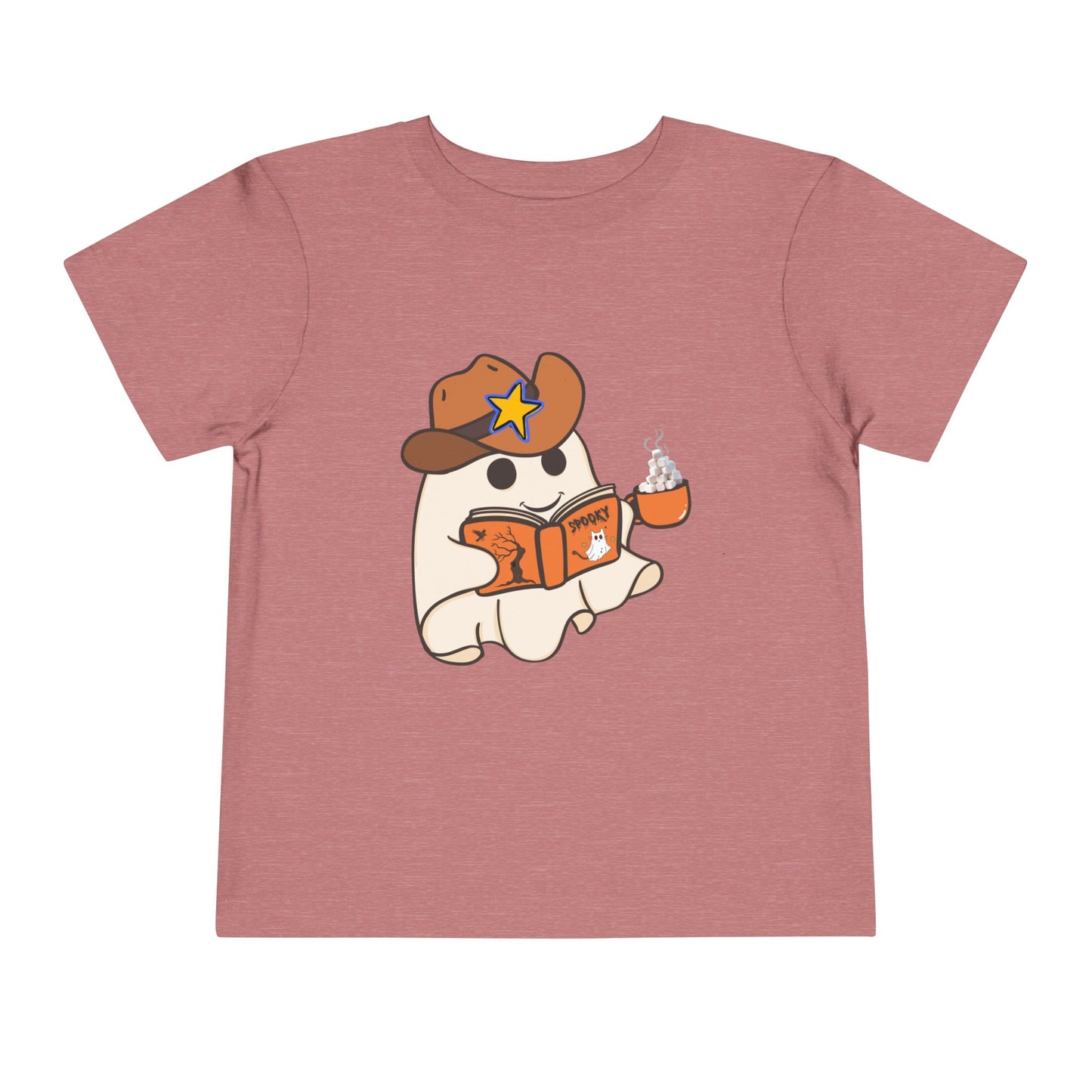 Pink toddler t-shirt with a cartoon ghost, wearing a cowboy hat, reading a spooky book and holding a cup of hot cocoa