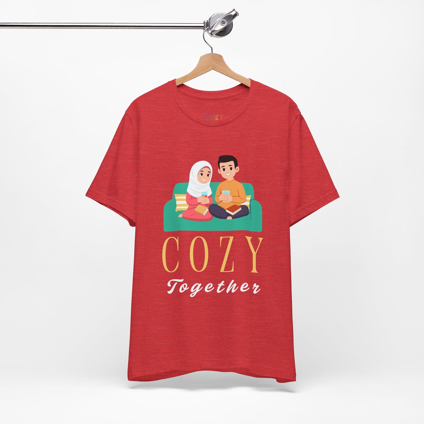 Red t-shirt with a graphic of two people on a couch, with books and drinks, the text 'Cozy Together' sits beneath in large letters