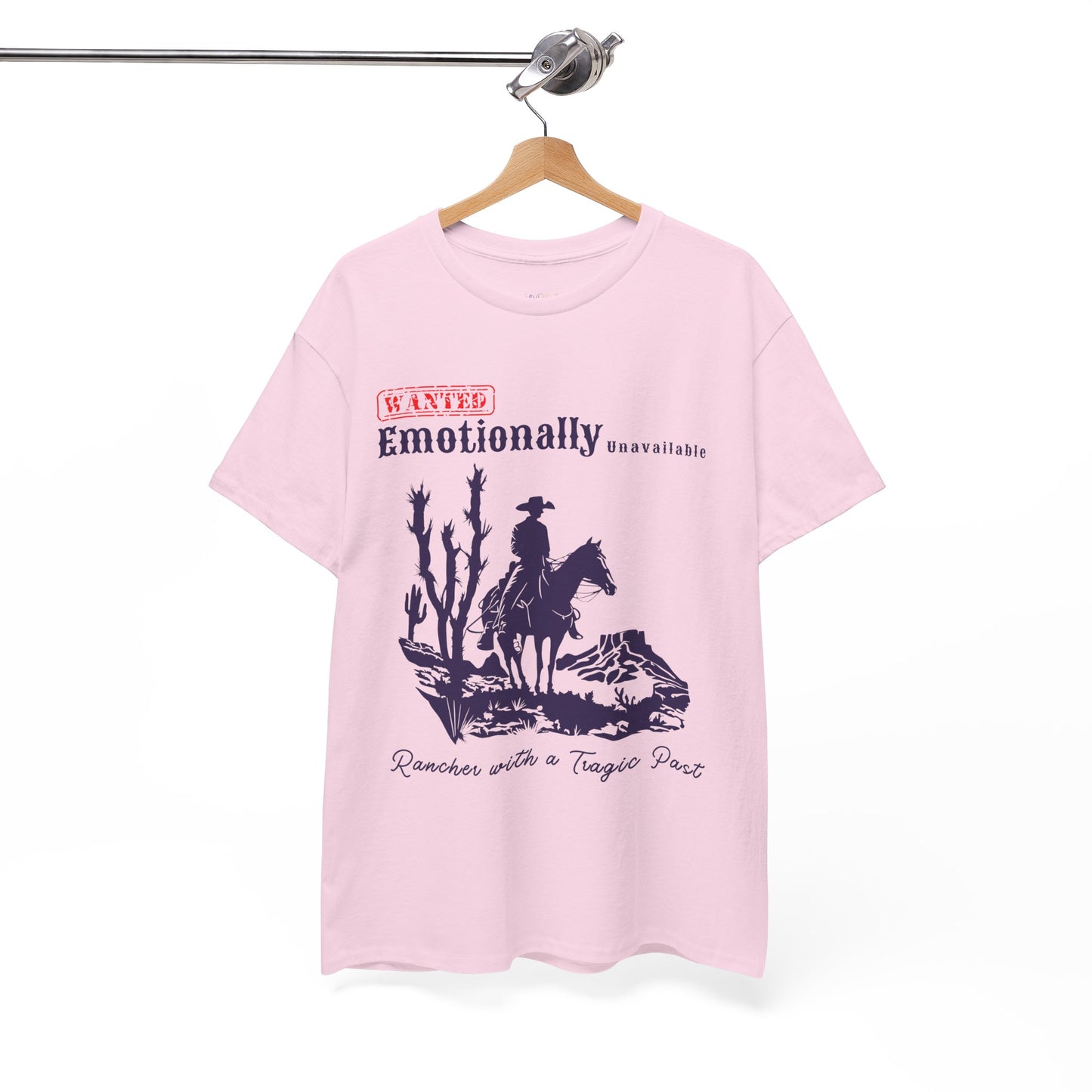 Pink t-shirt with a horse riding cowboy in a desert setting and text 'WANTED Emotionally Unavailable Rancher With A Tragic Past'