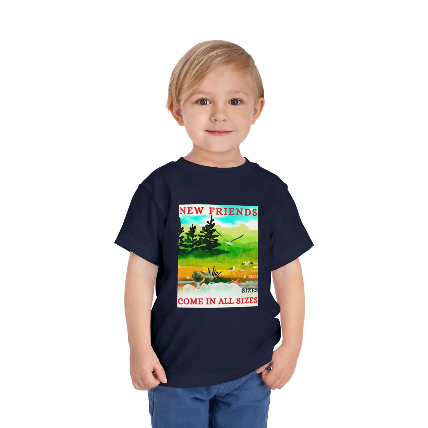 Child wearing a navy blue toddler t-shirt with a colorful nature beach scene and text 'New Friends Come in All Sizes'