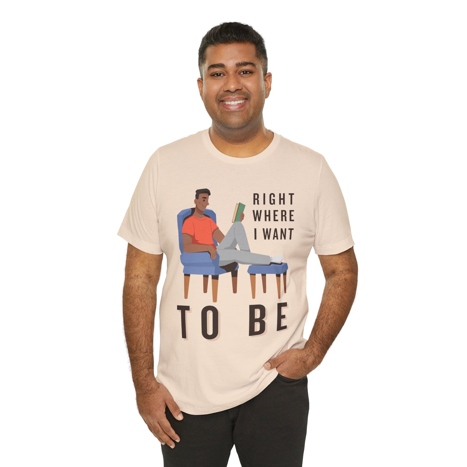 Man wearing a beige t-shirt with a man lounging in a chair, feet up, book in hand and text 'Right Where I Want To Be'
