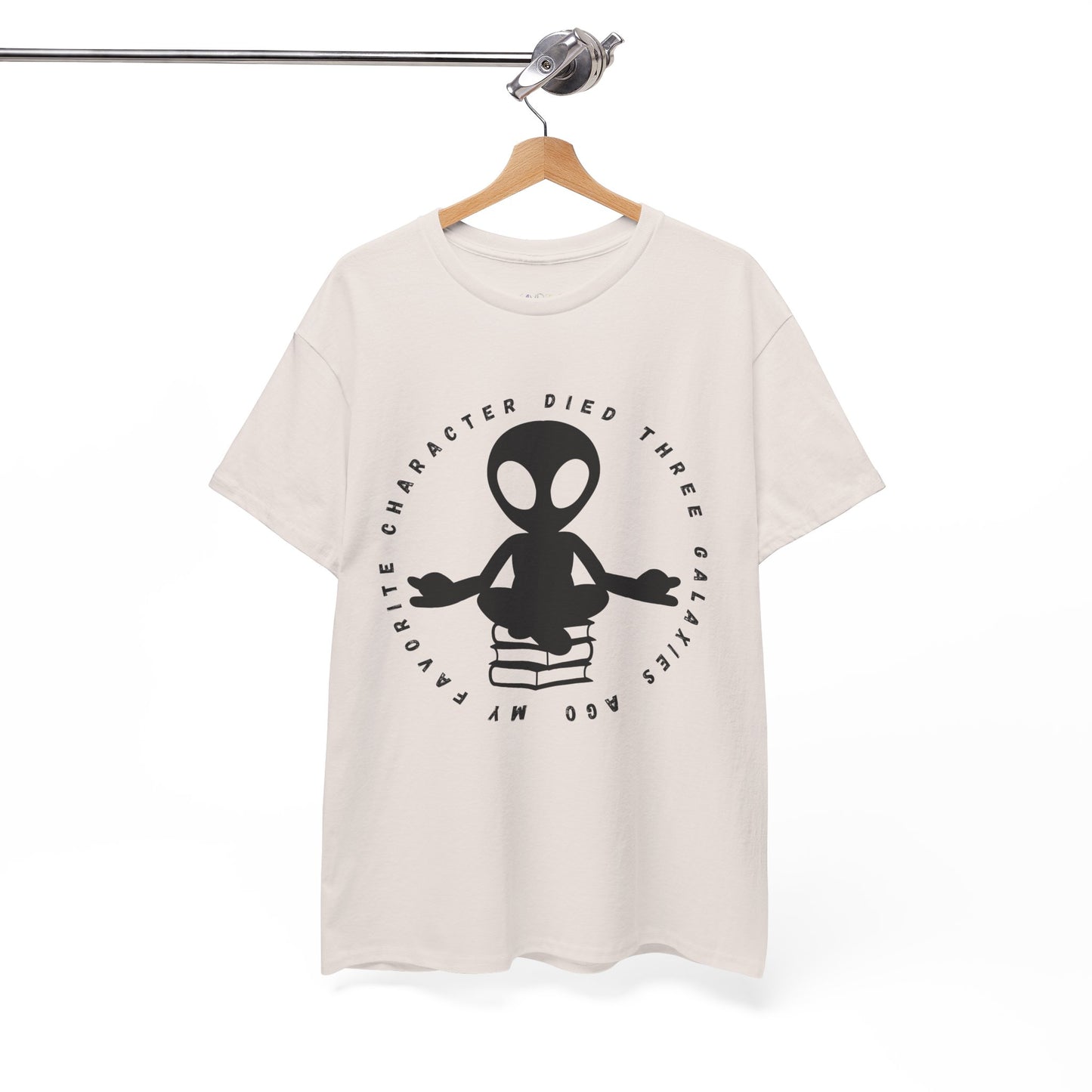 Beige t-shirt with meditating alien sitting on a stack of books, circled by text 'My Favorite Character Died Three Galaxies Ago' 