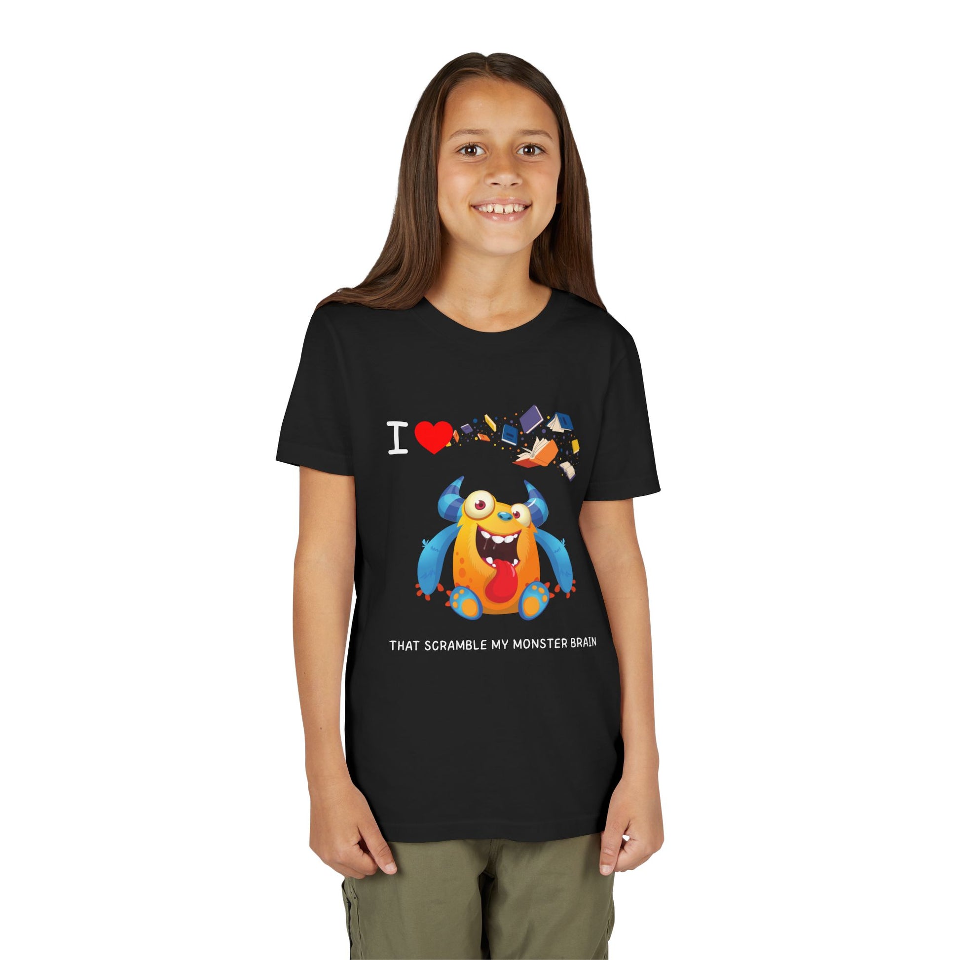 Girl wearing a black t-shirt with a goofy, yet colorful cartoon monster character, books flying through air and playful I love books that Scramble My Monster Brain text