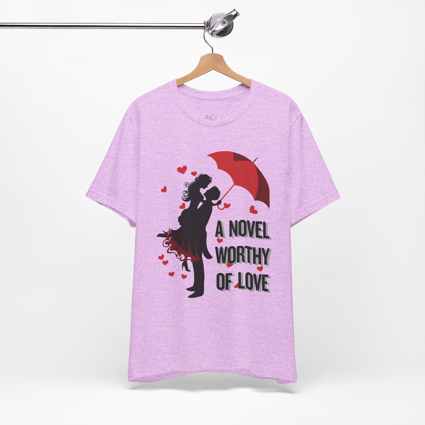 Light purple t-shirt with a black graphic design of a man holding a woman under a red umbrella, sprinkled with hearts and text 'A Novel Worthy of Love' 