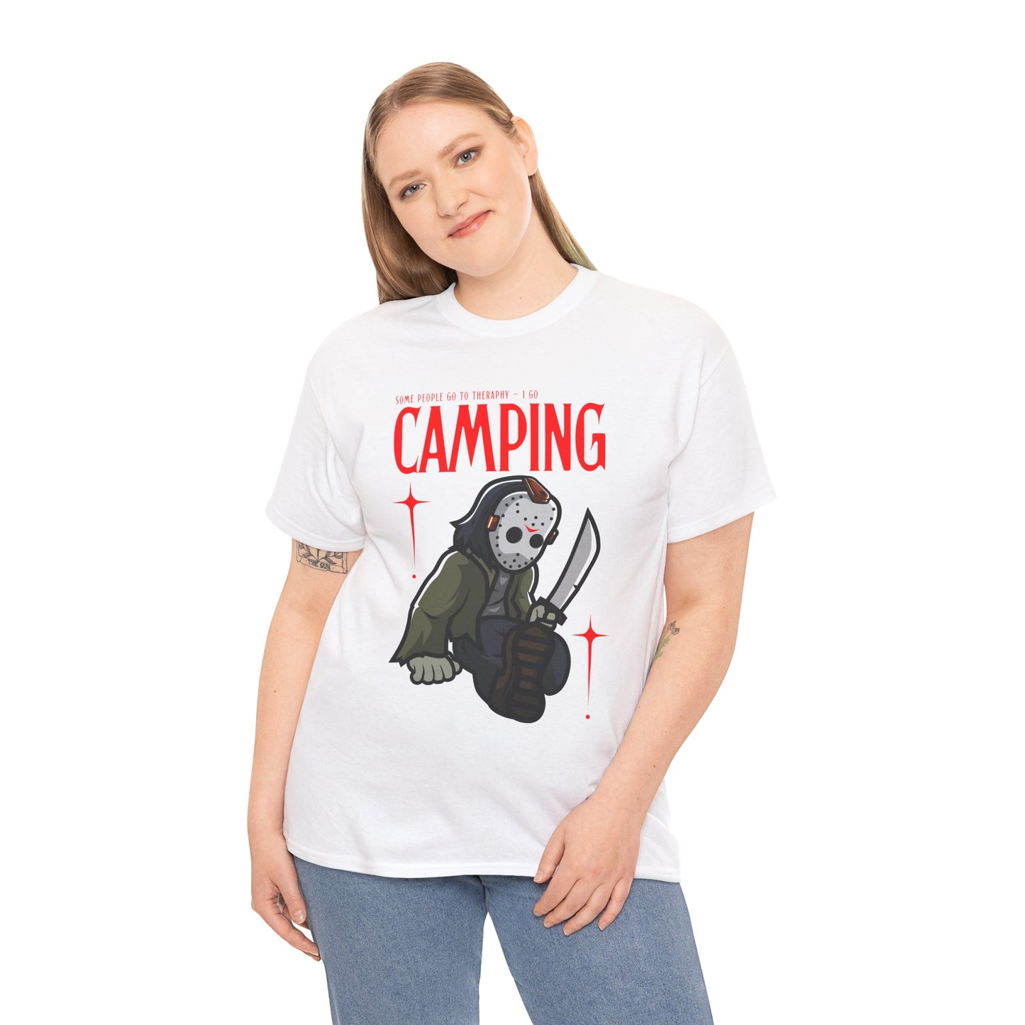 Woman wearing a white t-shirt with a graphic design of a Jason character holding a knife and text 'Some People Go to Therapy...I Go CAMPING' on a hanger against a white background.