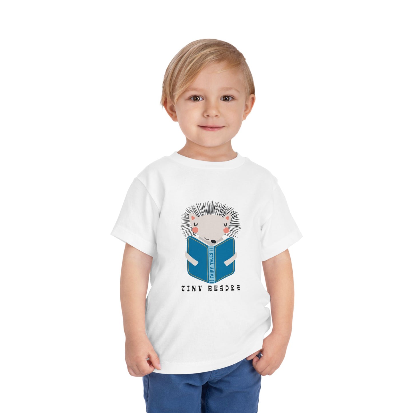 Toddler wearing a white t-shirt with a hedgehog reading a book graphic and 'Tiny Reader' text