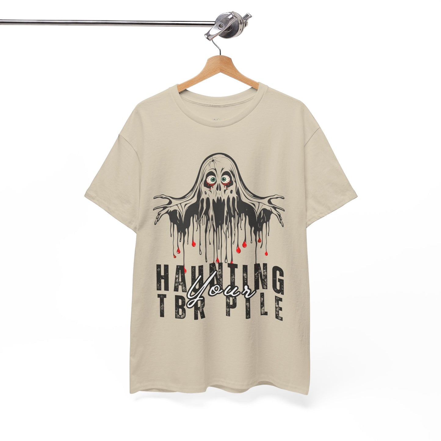 Tan t-shirt with ghost graphic and text 'Haunting Your TBR Pile' on a hanger against a white background