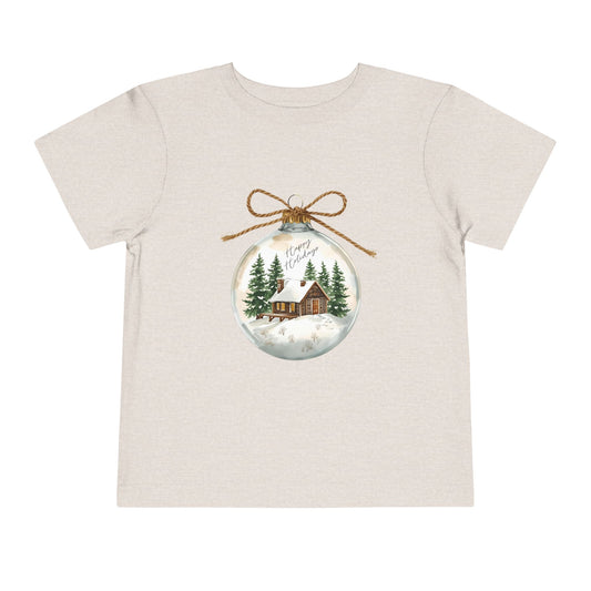 Beige t-shirt with a Christmas-themed ornament graphic featuring a cabin and trees.
