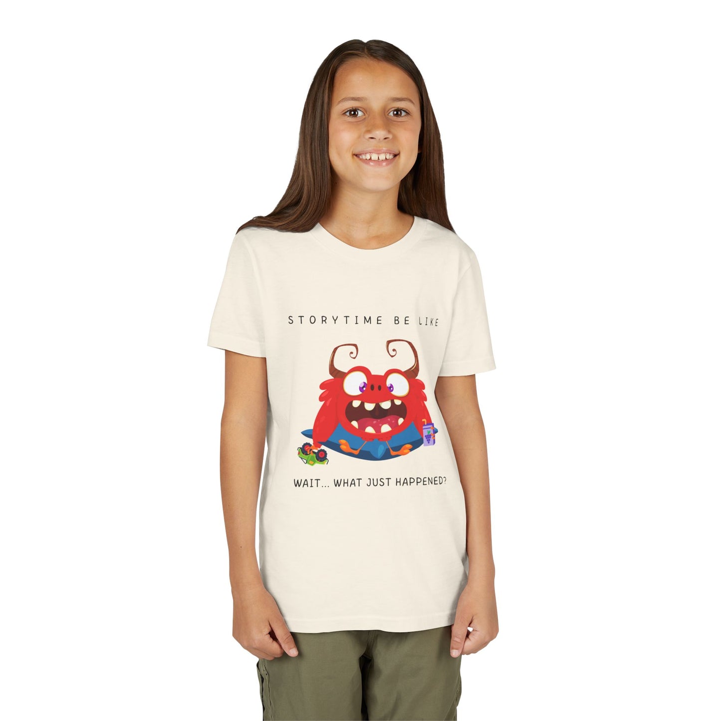 Girl wearing a beige t-shirt with a bewildered cartoon monster graphic sitting on a pillow, holding a car toy and a juice box, text 'Storytime be like wait...what just happened?'