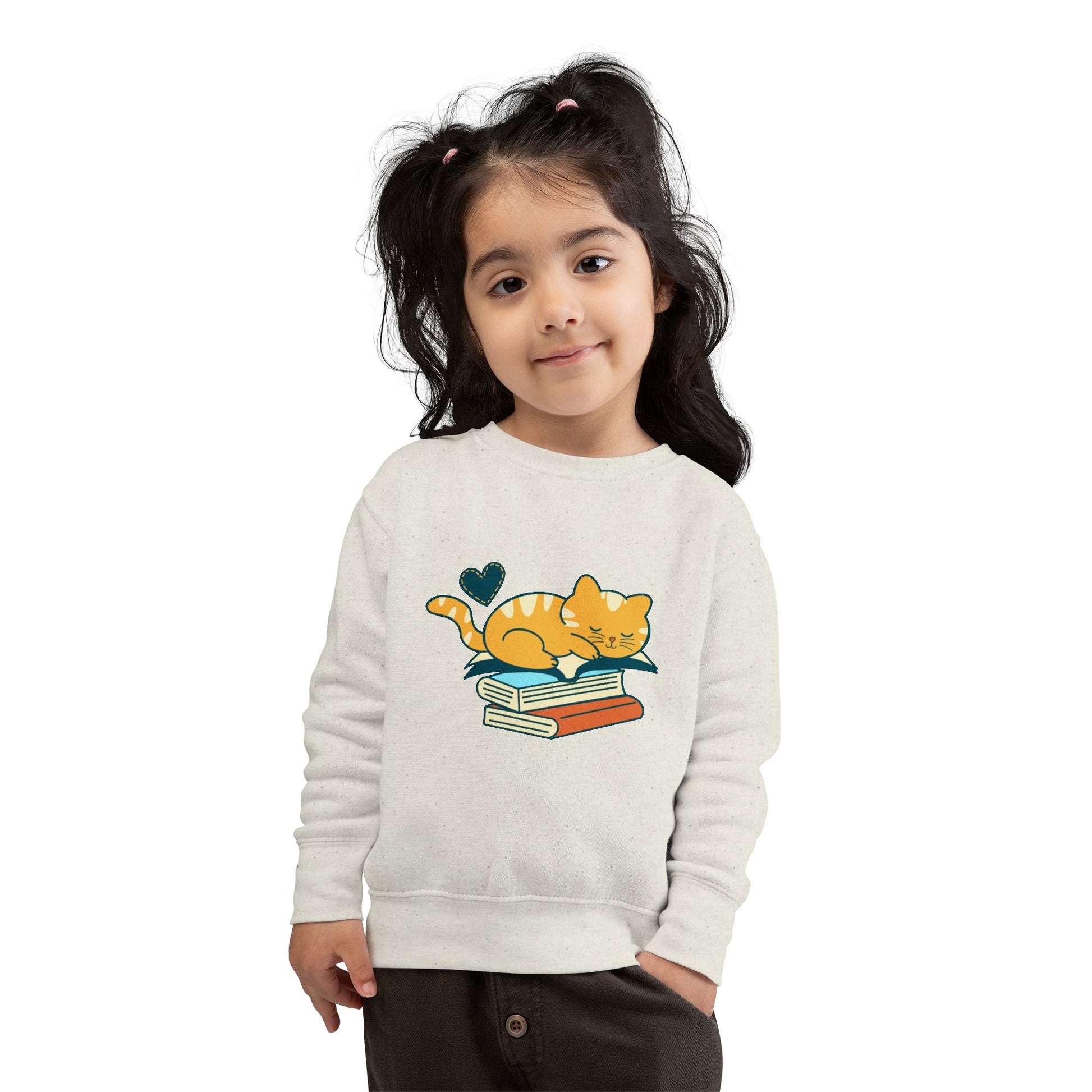 Girl wearing a beige toddler sweatshirt with a cat and snoozing on a stack of books