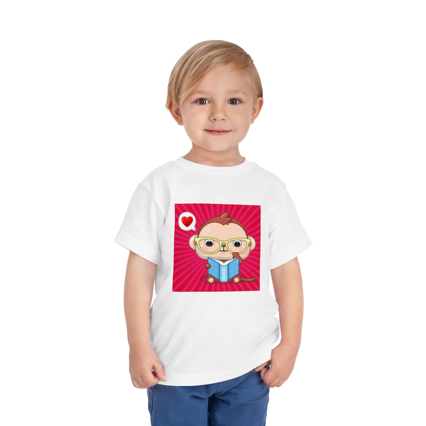 Toddler wearing a white t-shirt with a cartoon monkey in yellow eye glasses, reading a book, a heart thought bubble and red background