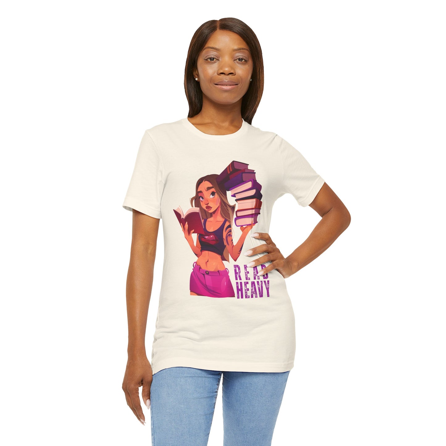 Woman wearing a beige t-shirt with a stylish woman graphic reading a book in one hand and holding a stack of books in the other, and the text 'Read Heavy' 