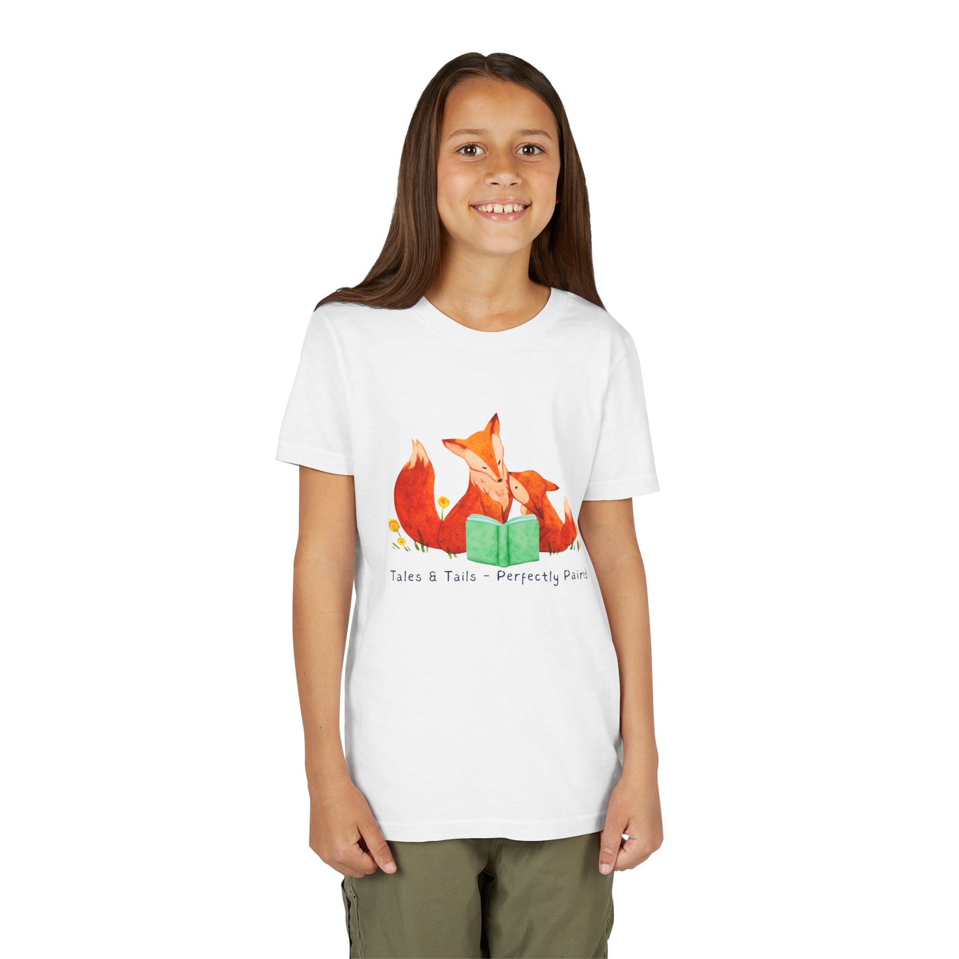Girl wearing a white t-shirt with fox family reading a book and text 'tales & tails - perfectly paired'