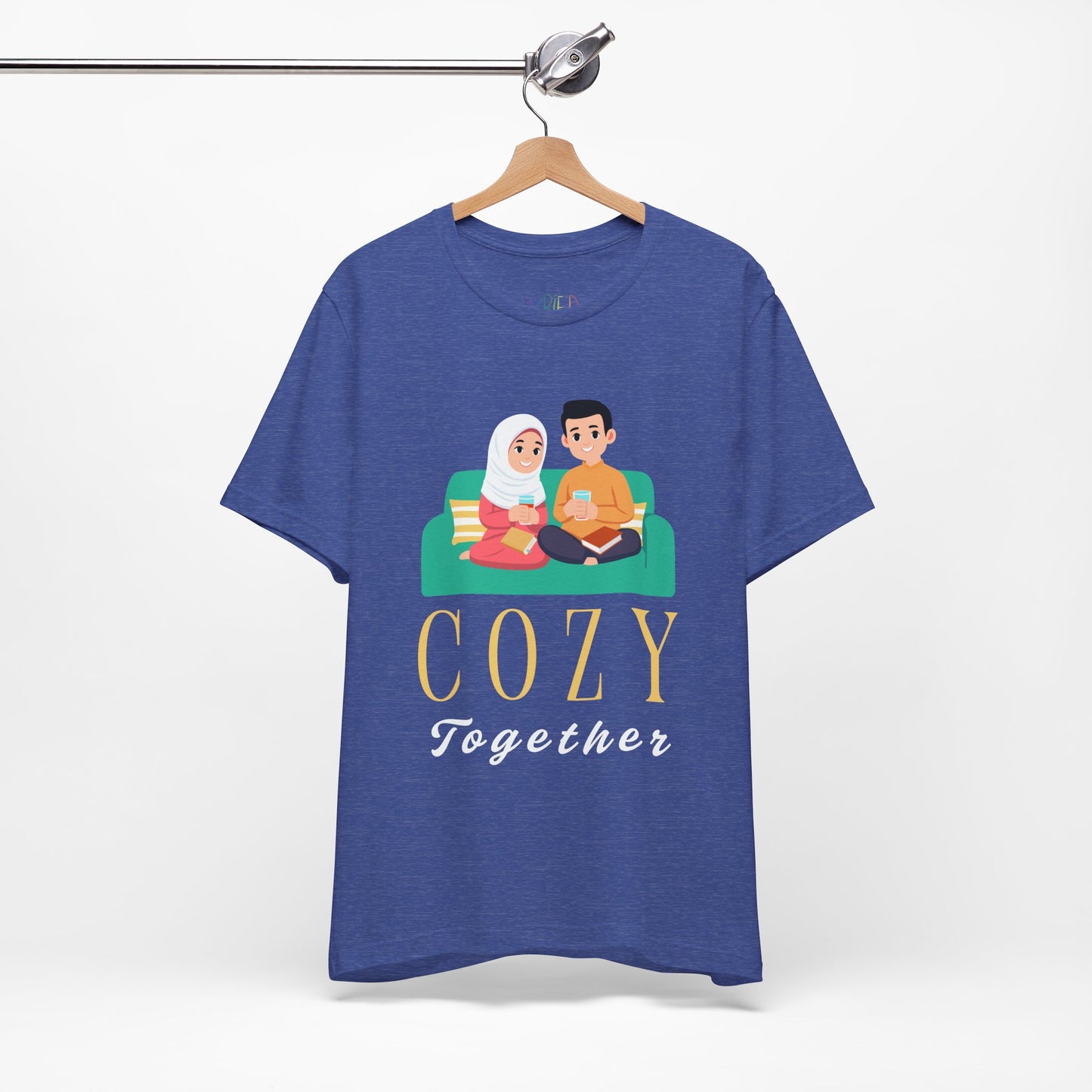 Blue t-shirt with a graphic of two people on a couch, with books and drinks, the text 'Cozy Together' sits beneath in large letters