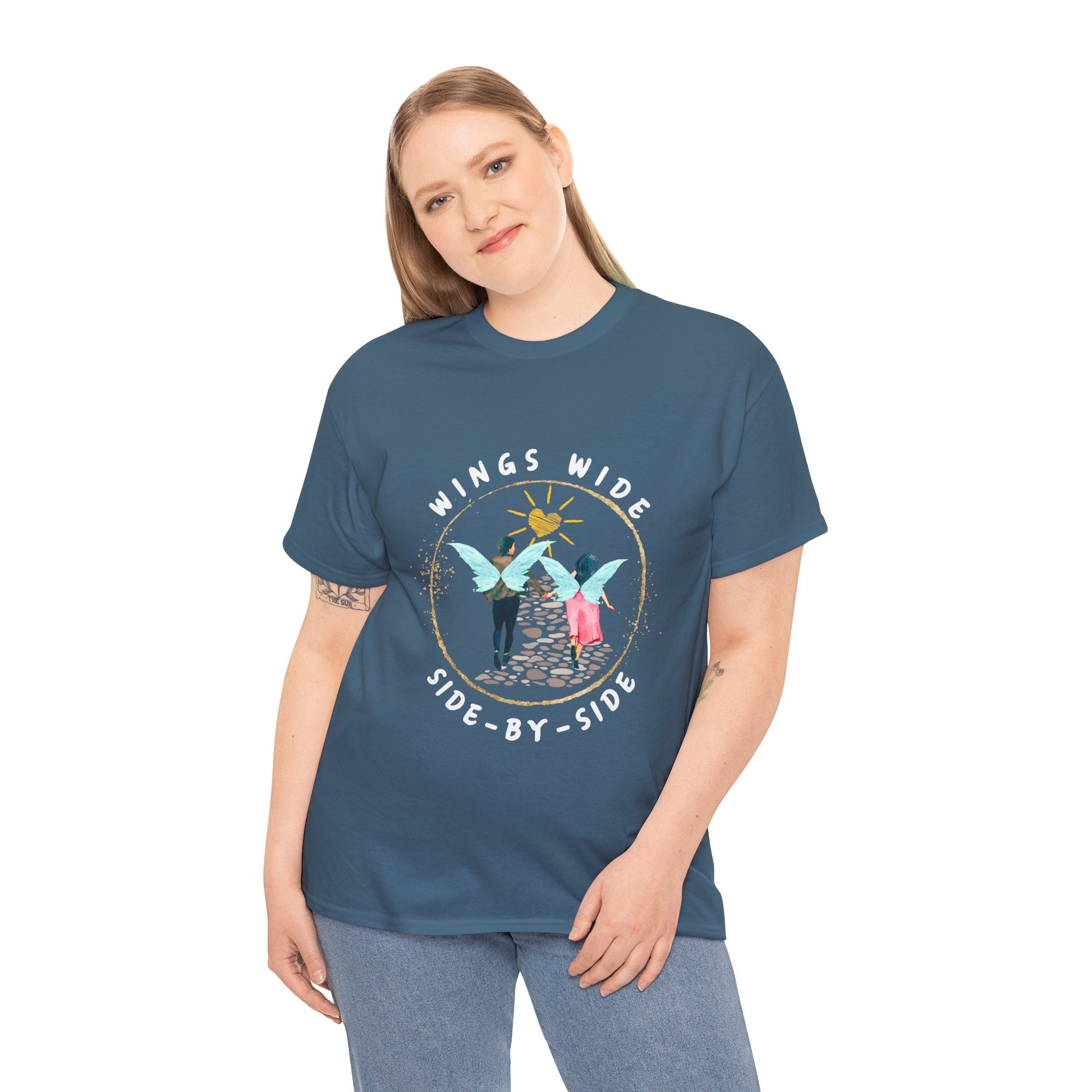Woman wearing a teal t-shirt with a fairy couple running off into the sunset down a cobblestone path and text 'Wings Wide Side-By-Side'