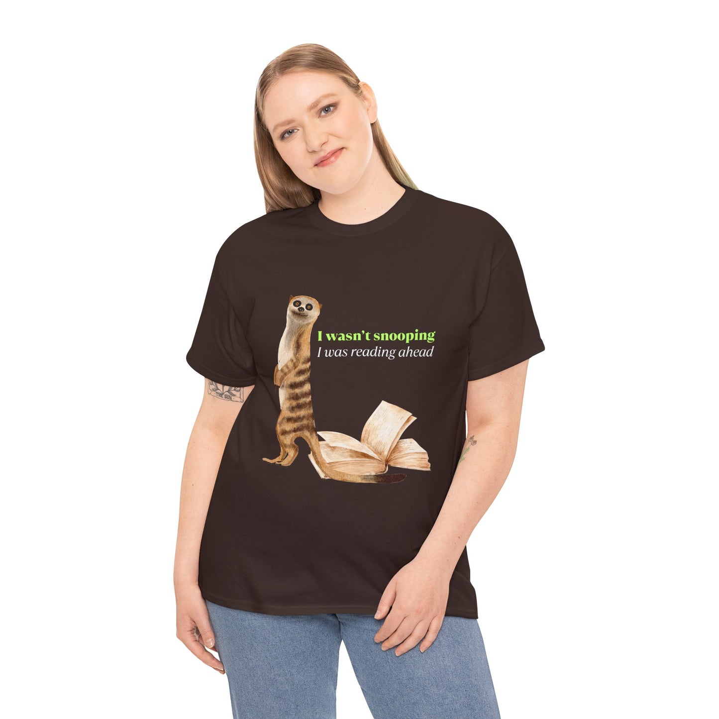 Woman wearing a brown t-shirt with a sheepish meerkat, back to an open book, text 'I Wasn't Snooping, I Was Reading Ahead'