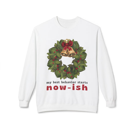 White sweatshirt with a Christmas wreath design and text 'my best behavior starts now-ish' on a white background