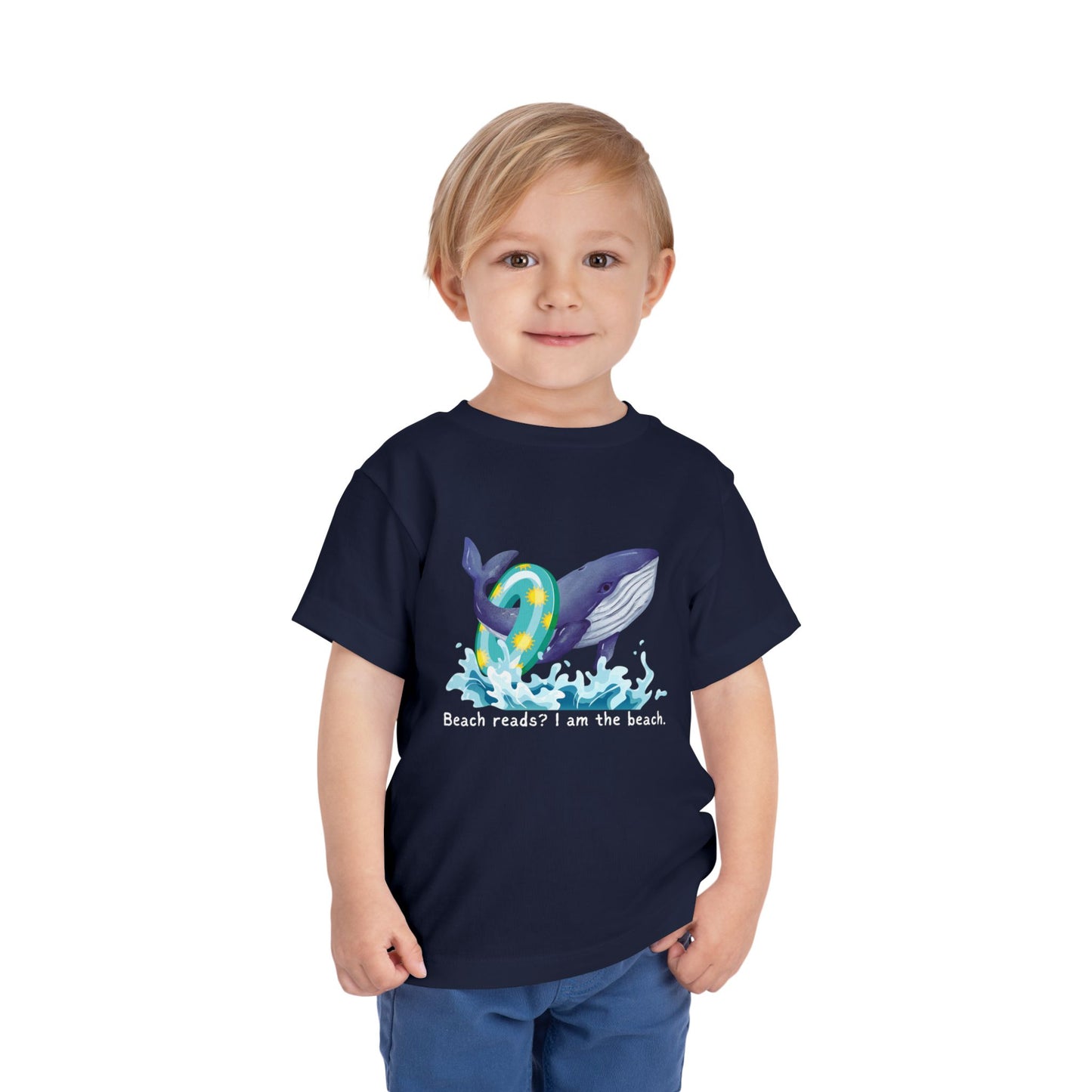 Child wearing a navy blue toddler t-shirt with a whale graphic jumping out of the water with a pool floatie and text 'Beach reads? I am the beach.' 