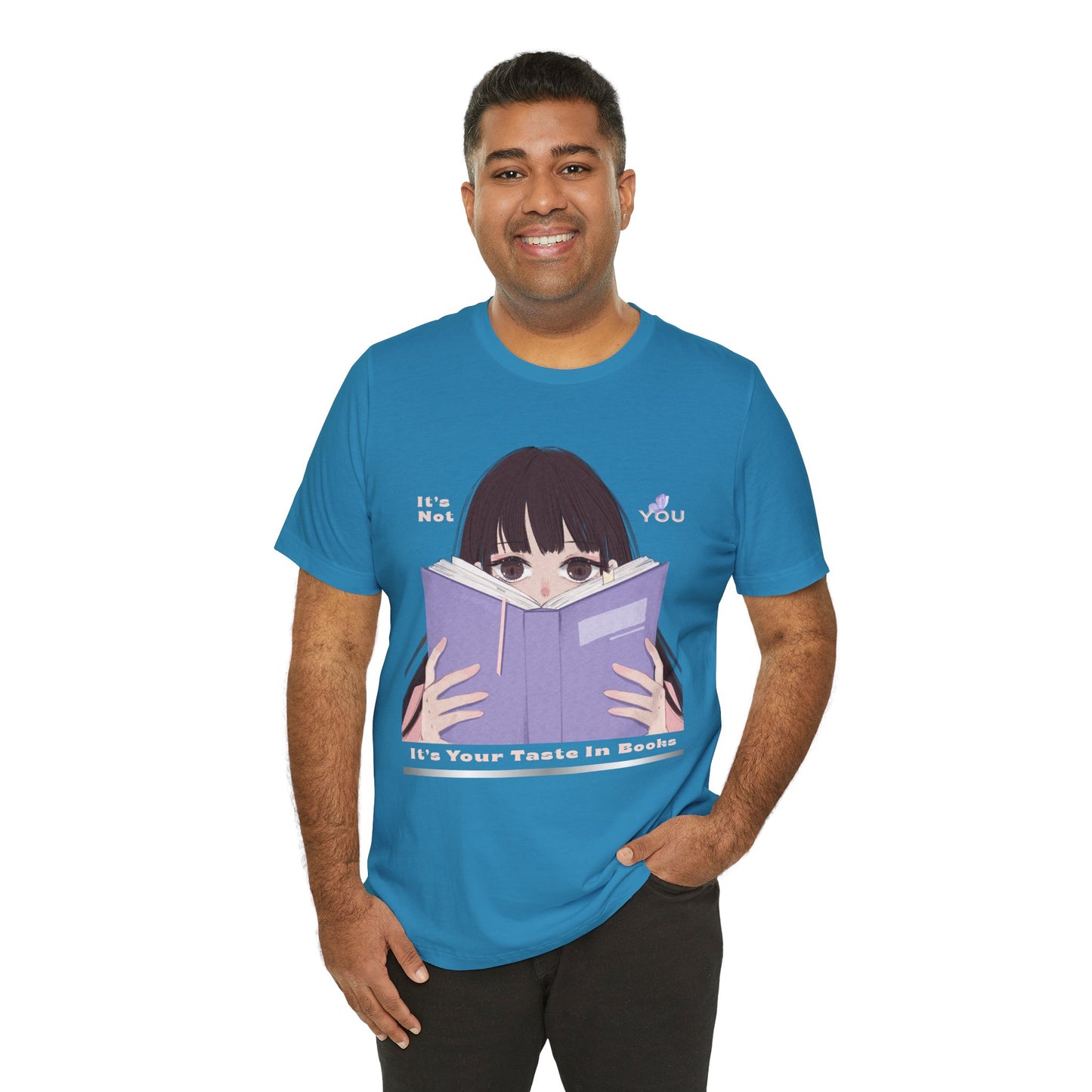 Man wearing a blue t-shirt with graphic design of a girl peeking over the top of a book and text 'It's Not You. It's Your Taste In Books.'