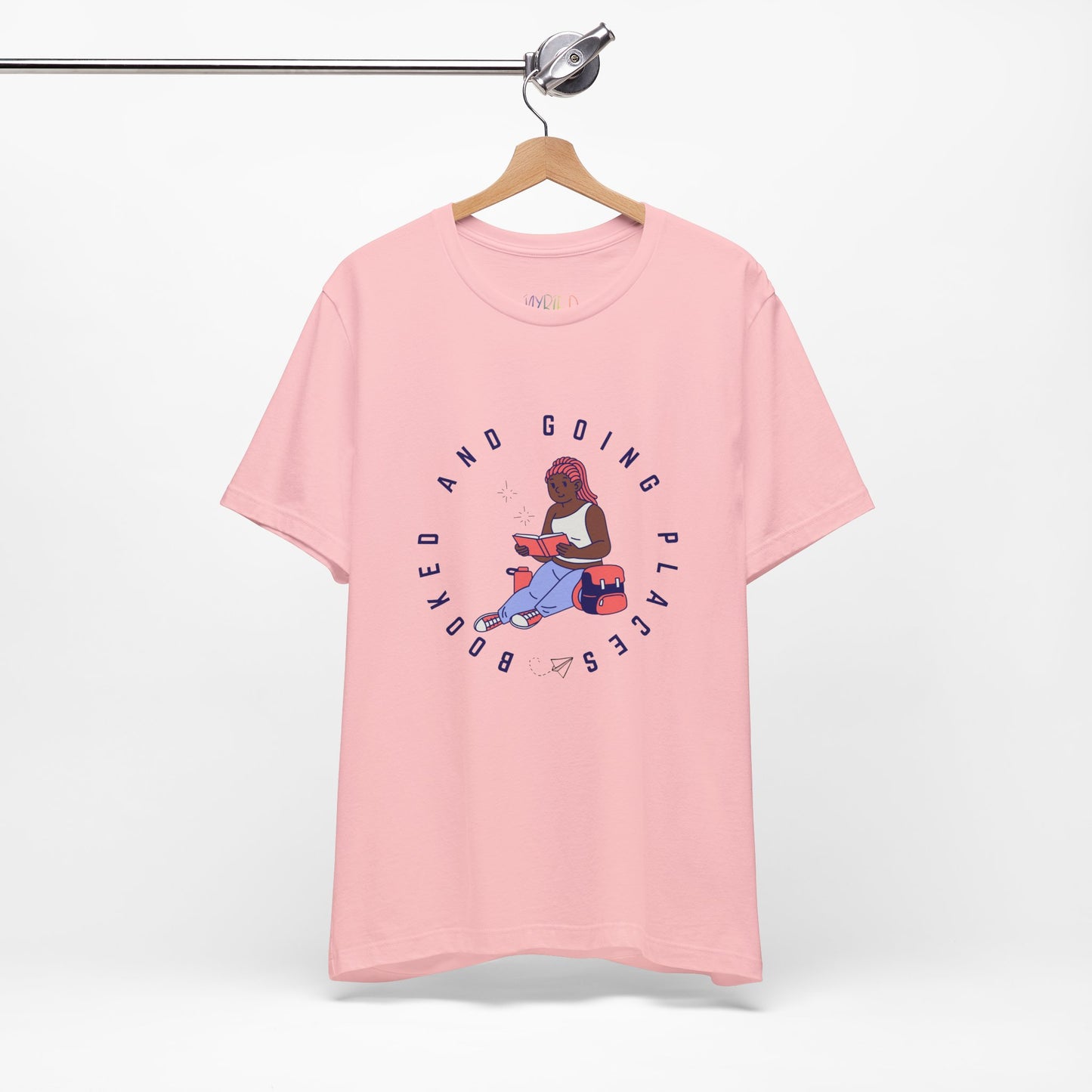Pink t-shirt with graphic design of a school girl sitting with a book and text 'Booked And Going Places'