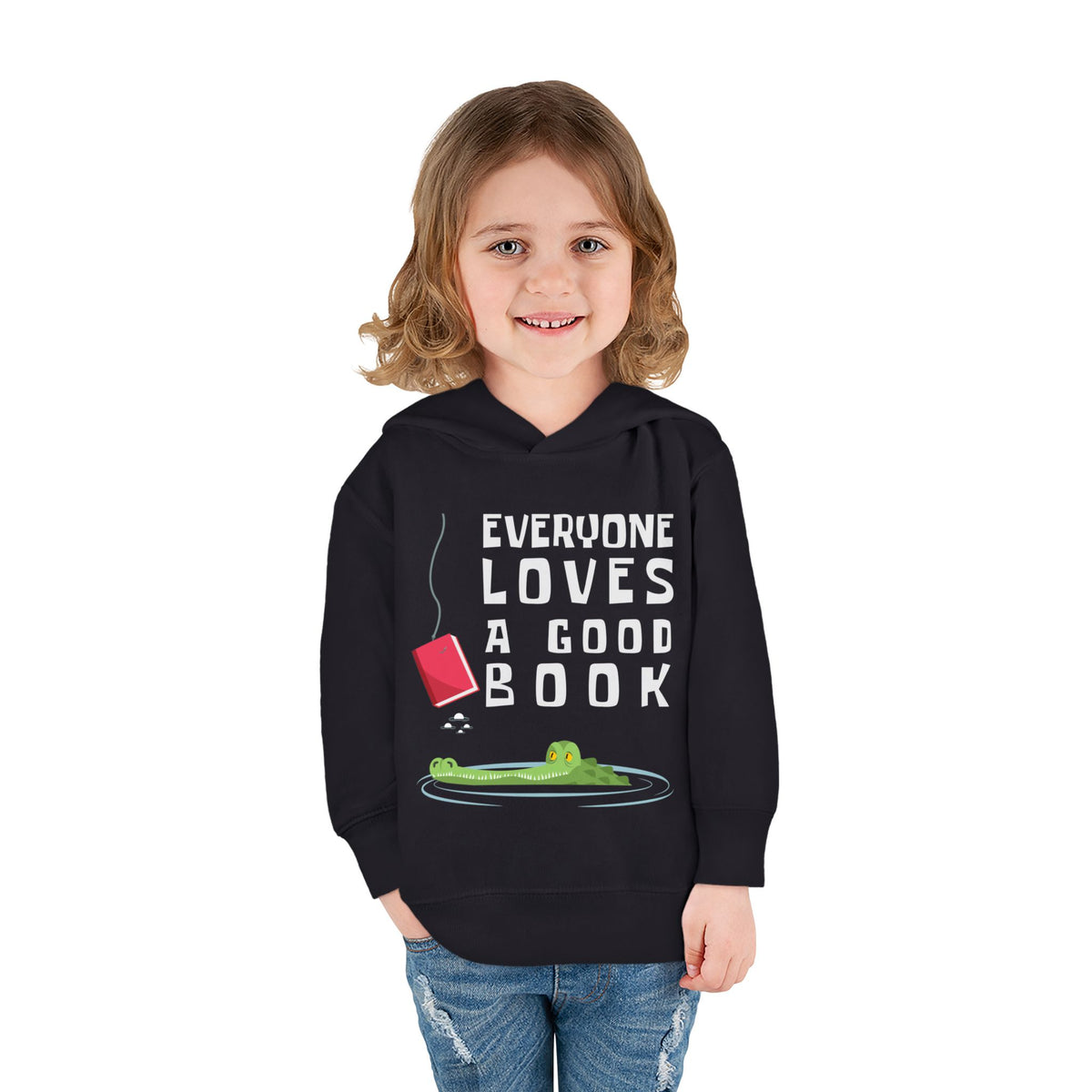 Little girl wearing a black toddler pullover hoodie with a graphic print on the front. The print features the text 'EVERYONE LOVES A GOOD BOOK' in white capital letters, accompanied by an illustration of a green alligator in a pool of water with a red book hanging above it, on a solid white background.