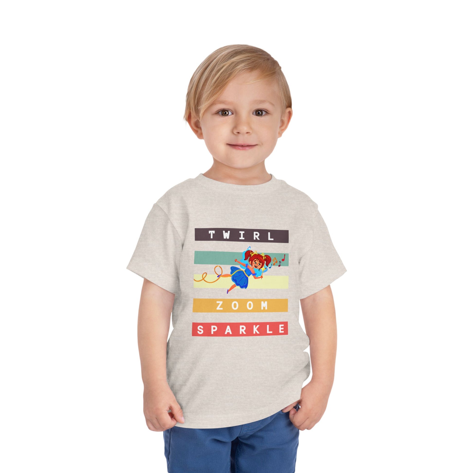 Child wearing a tan toddler t-shirt with a flying fairy and text in colorful stripes 'twirl, zoom sparkle' 