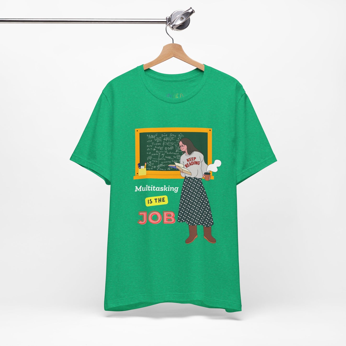 Green t-shirt with a graphic design of a woman at a chalkboard, an open book in one hand and steaming coffee in the other, text 'Multitasking is the Job' 