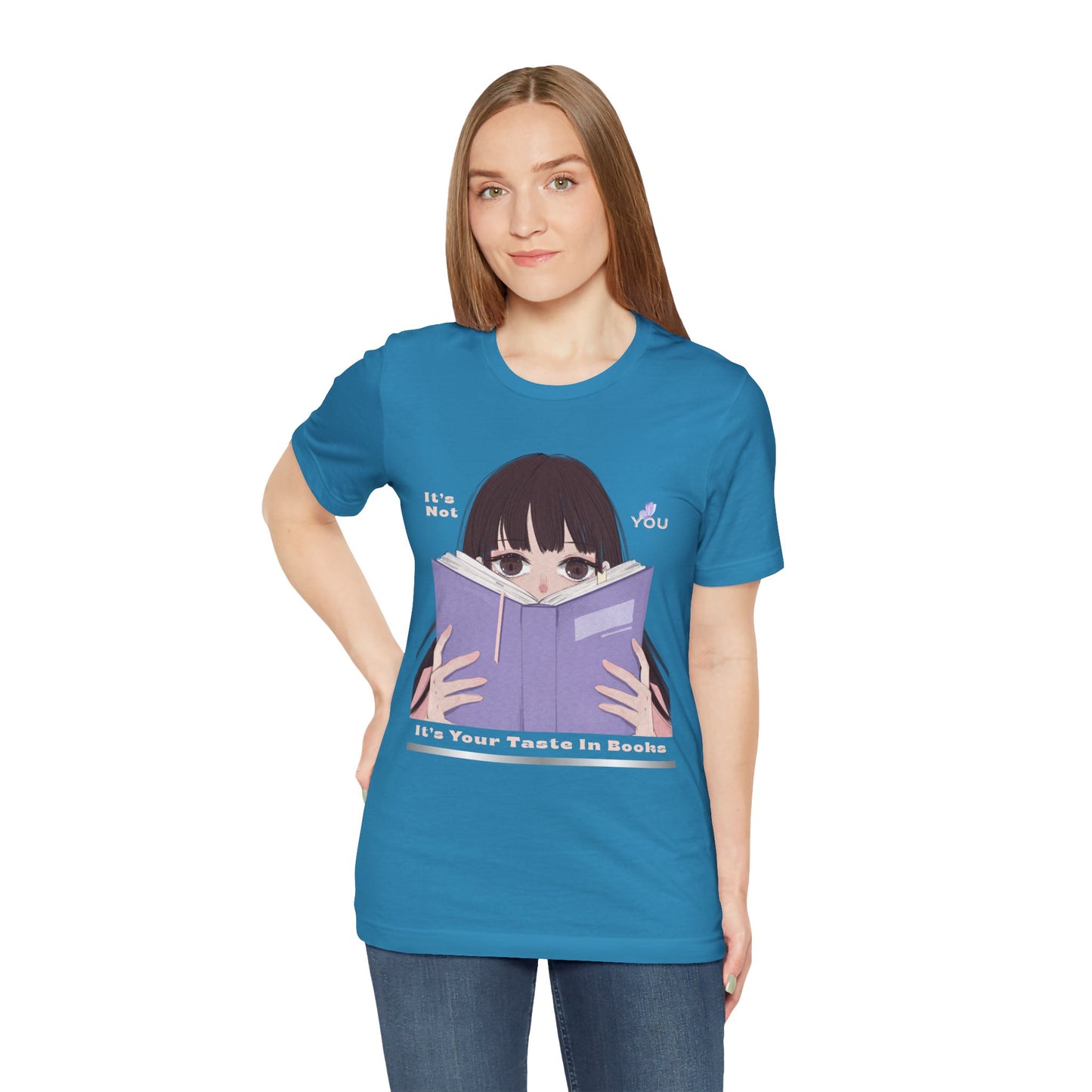 Woman wearing a blue t-shirt with graphic design of a girl peeking over the top of a book and text 'It's Not You. It's Your Taste In Books.'