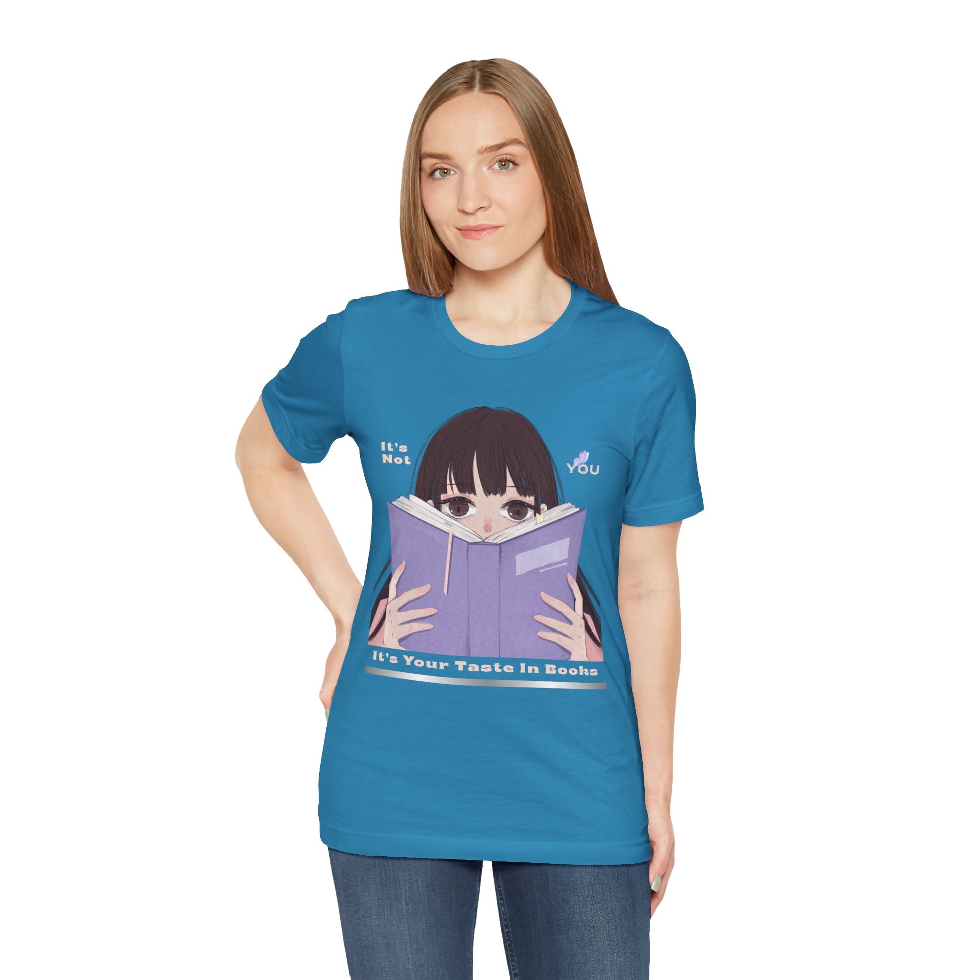 Woman wearing a blue t-shirt with graphic design of a girl peeking over the top of a book and text 'It's Not You. It's Your Taste In Books.'