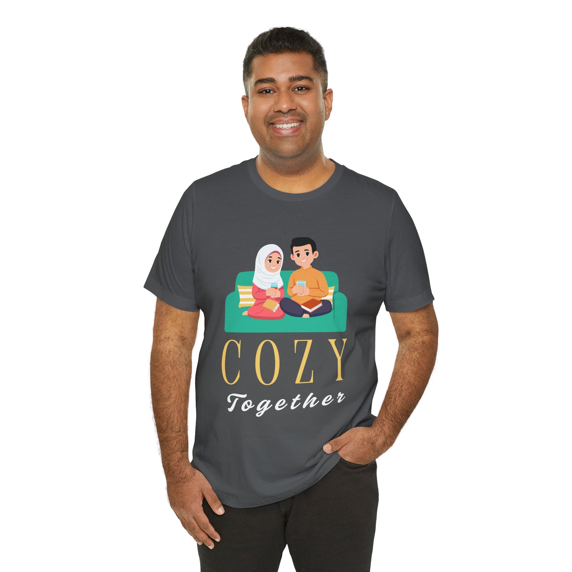 Man wearing a gray t-shirt with a graphic of two people on a couch, with books and drinks, the text 'Cozy Together' sits beneath in large letters