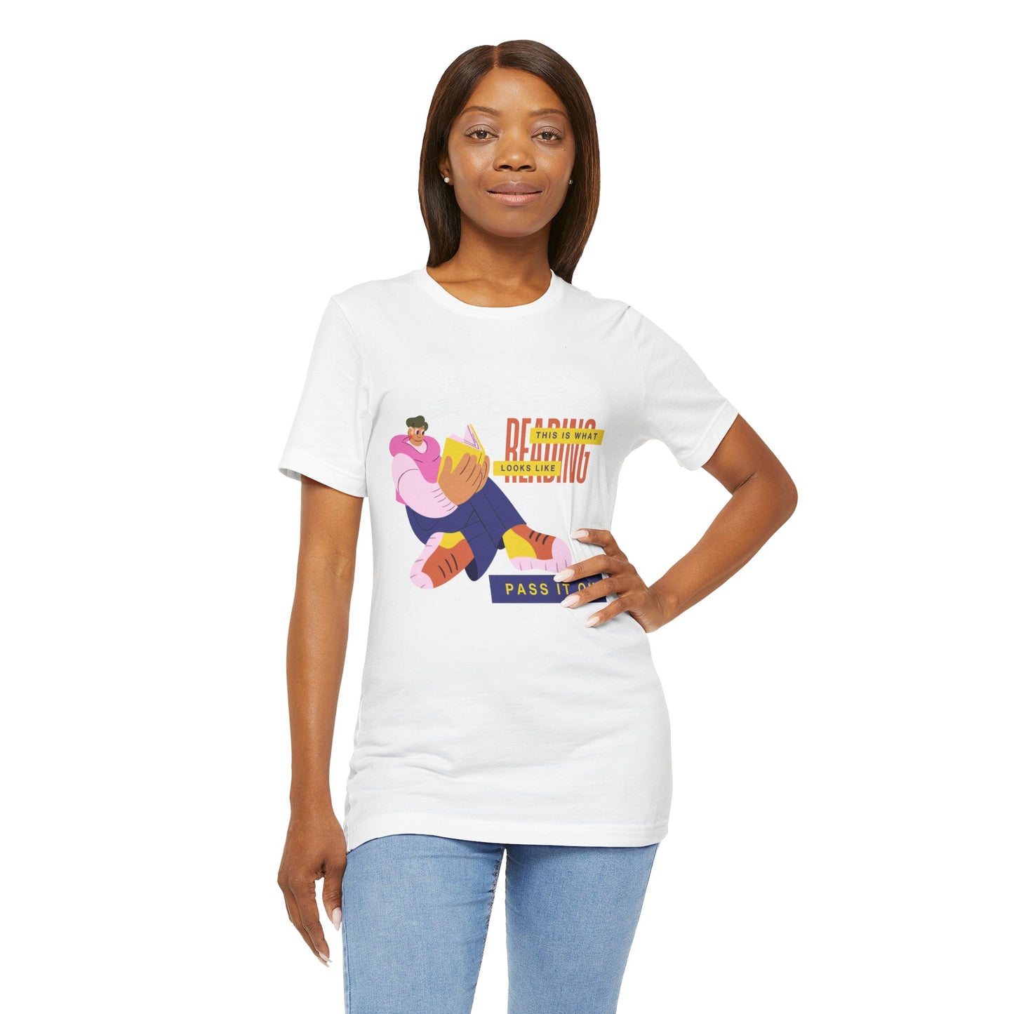 Woman wearing a white t-shirt with colorful, funny shaped figure reading a book and text 'This Is What Reading Looks Like, Pass It On'