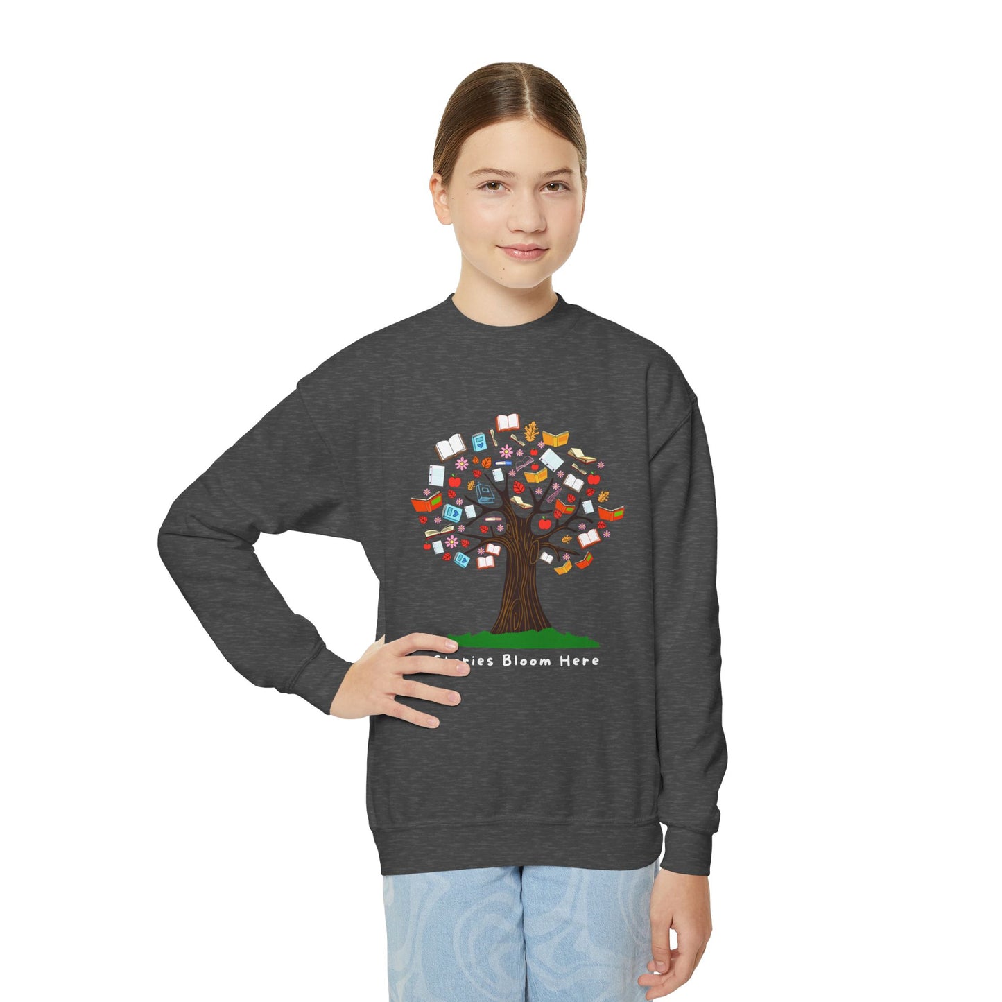 Girl wearing a dark gray sweatshirt with a colorful tree graphic with books for leaves and text 'Stories Bloom Here' 