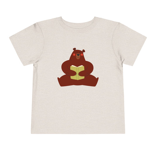 Sandy beige t-shirt with a blushing sear holding a book 