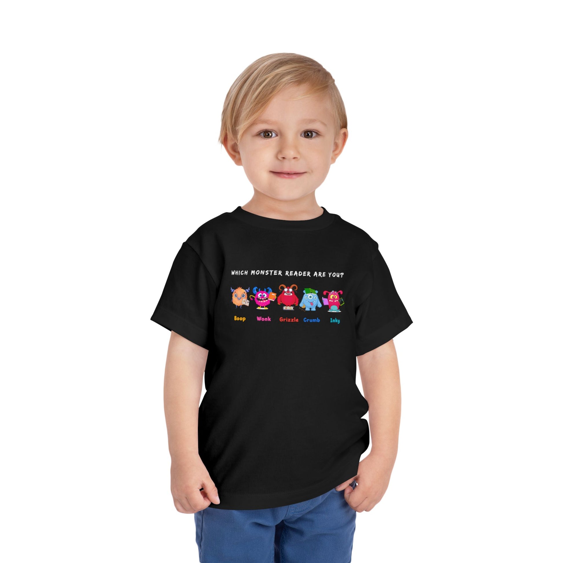 Child wearing a black toddler personality t-shirt with colorful monsters lined up in a row and text 'Which Monster Reader Are You?' Monster names 'Boop, Wonk, Grizzle, Crump, Inky' on white background
