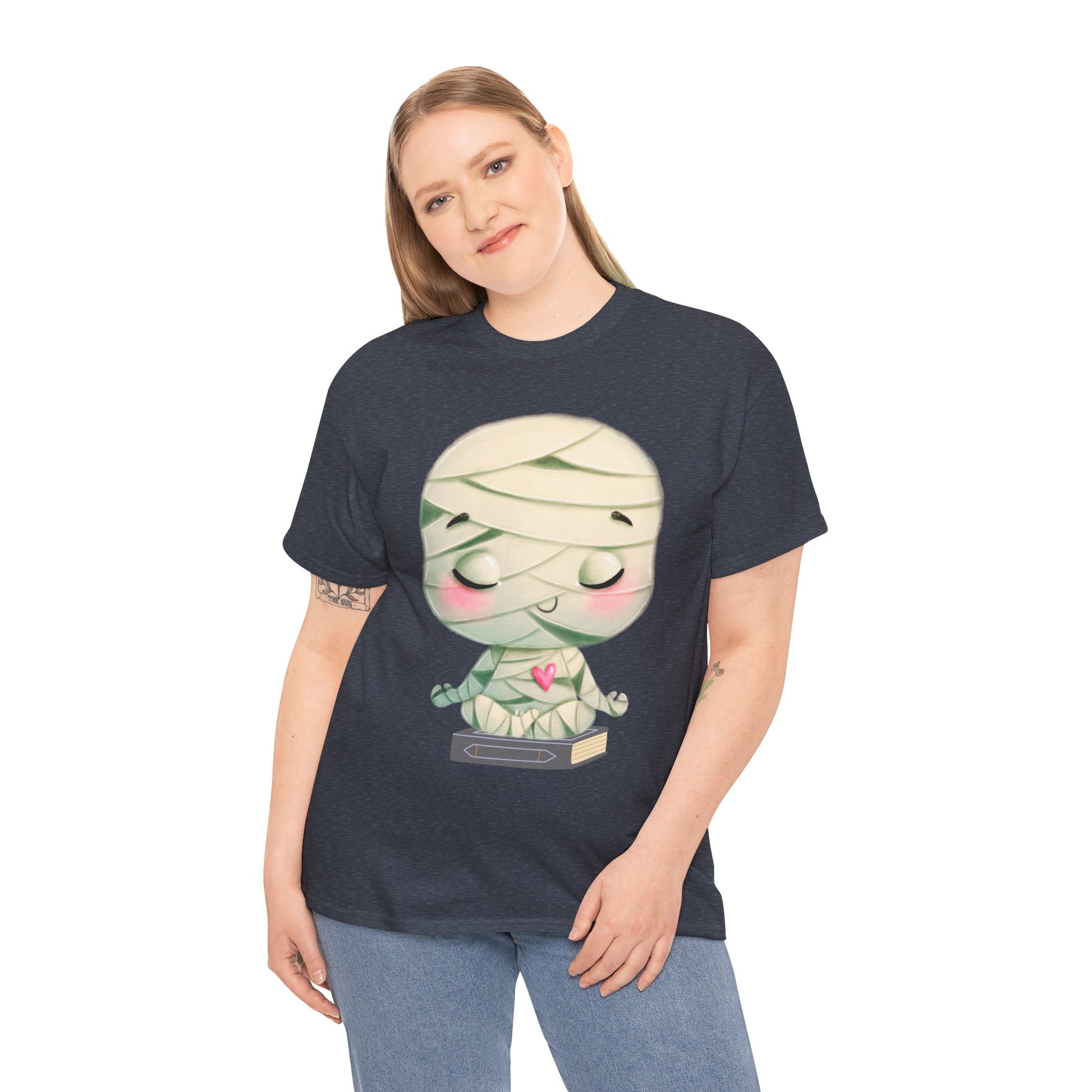 Woman wearing a heather navy t-shirt with a cartoon mummy in a meditation pose, sitting on a book
