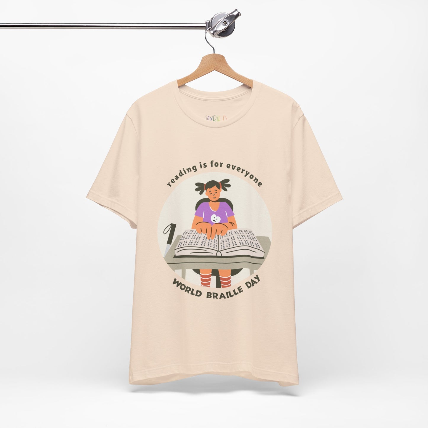 Beige t-shirt with a girl reading a book in braille and text circling that says 'Reading Is For Everyone, World Braille Day' 