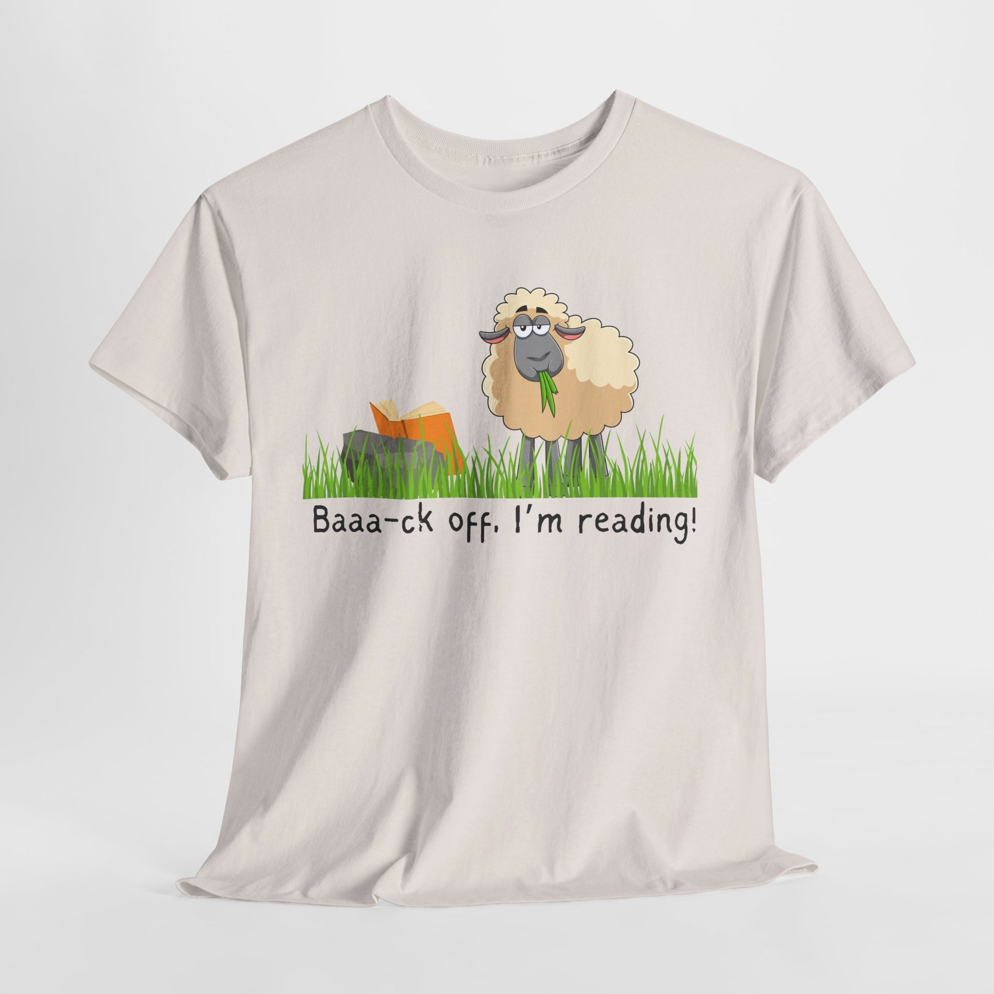 Beige t-shirt with a cartoon sheep munching on grass while reading a book propped up on a rock, text 'Baaa-ck off. I'm reading!' 