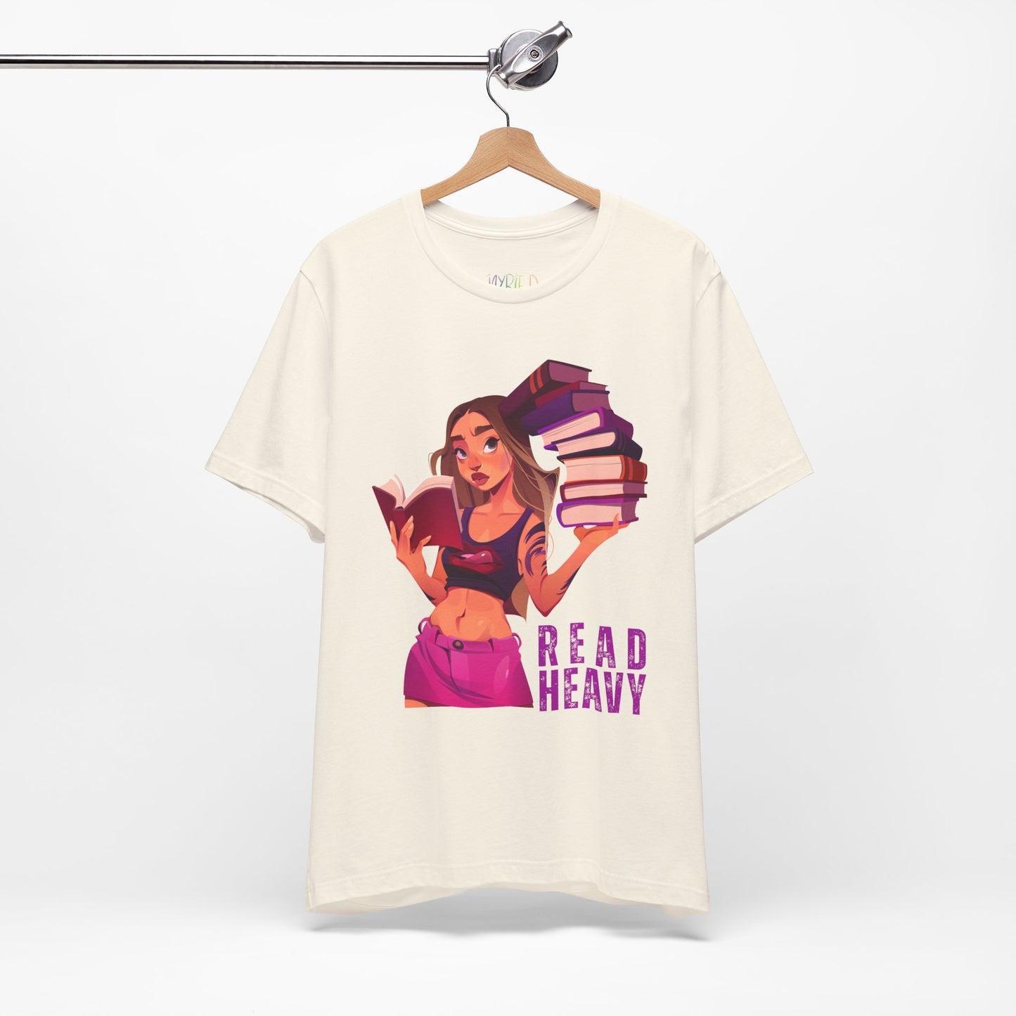 Beige t-shirt with a stylish woman graphic reading a book in one hand and holding a stack of books in the other, and the text 'Read Heavy' 