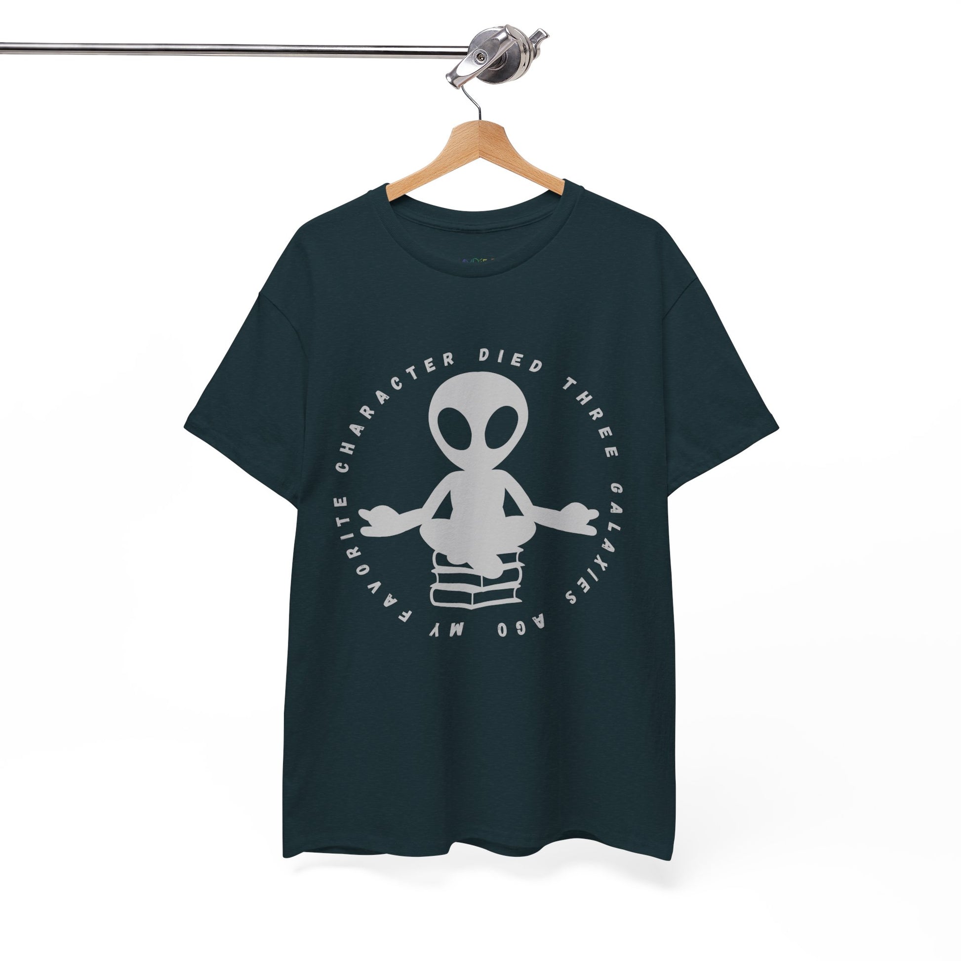 Dark t-shirt with meditating alien sitting on a stack of books, circled by text 'My Favorite Character Died Three Galaxies Ago' 