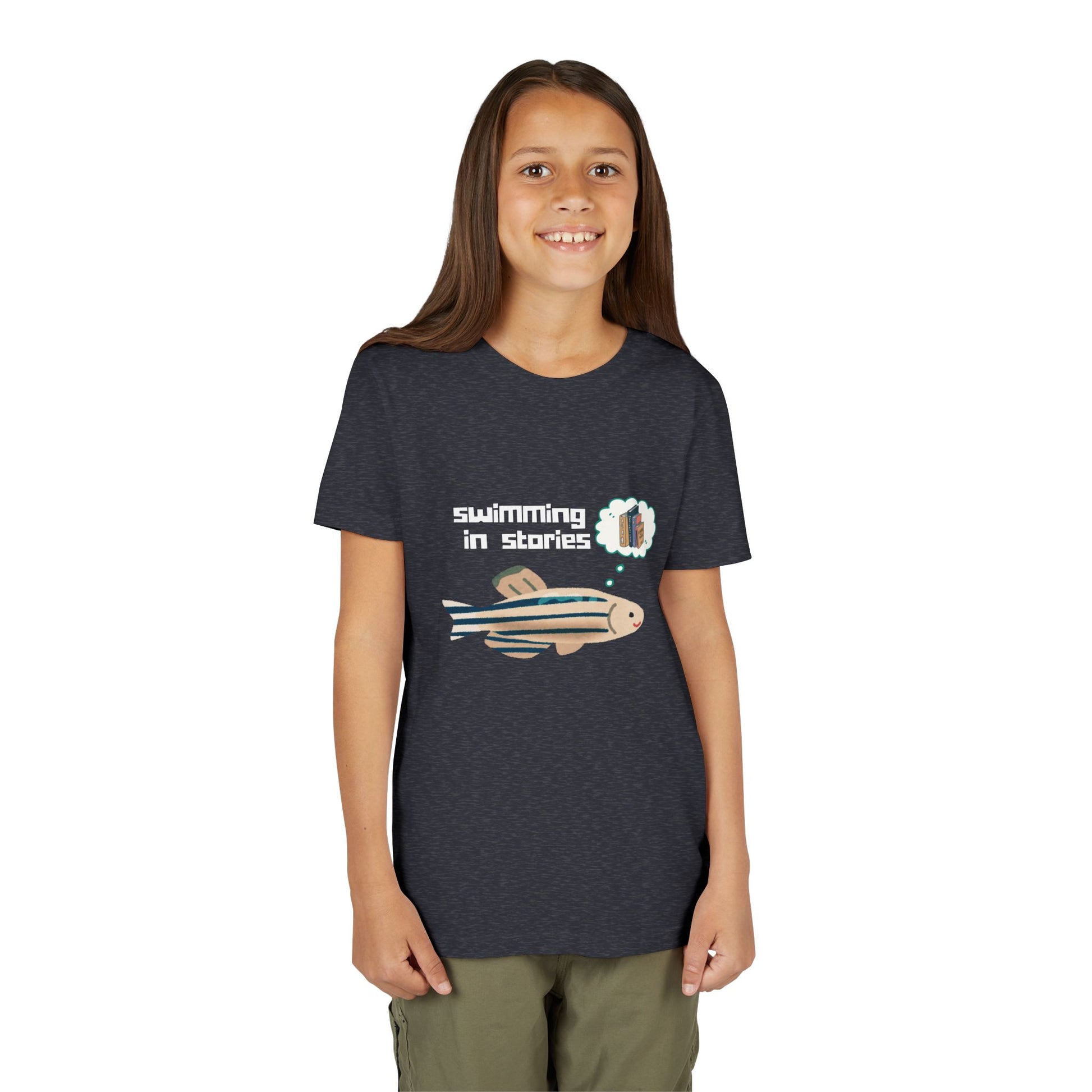 Girl wearing a navy blue t-shirt with a fish graphic and text 'swimming in stories' 