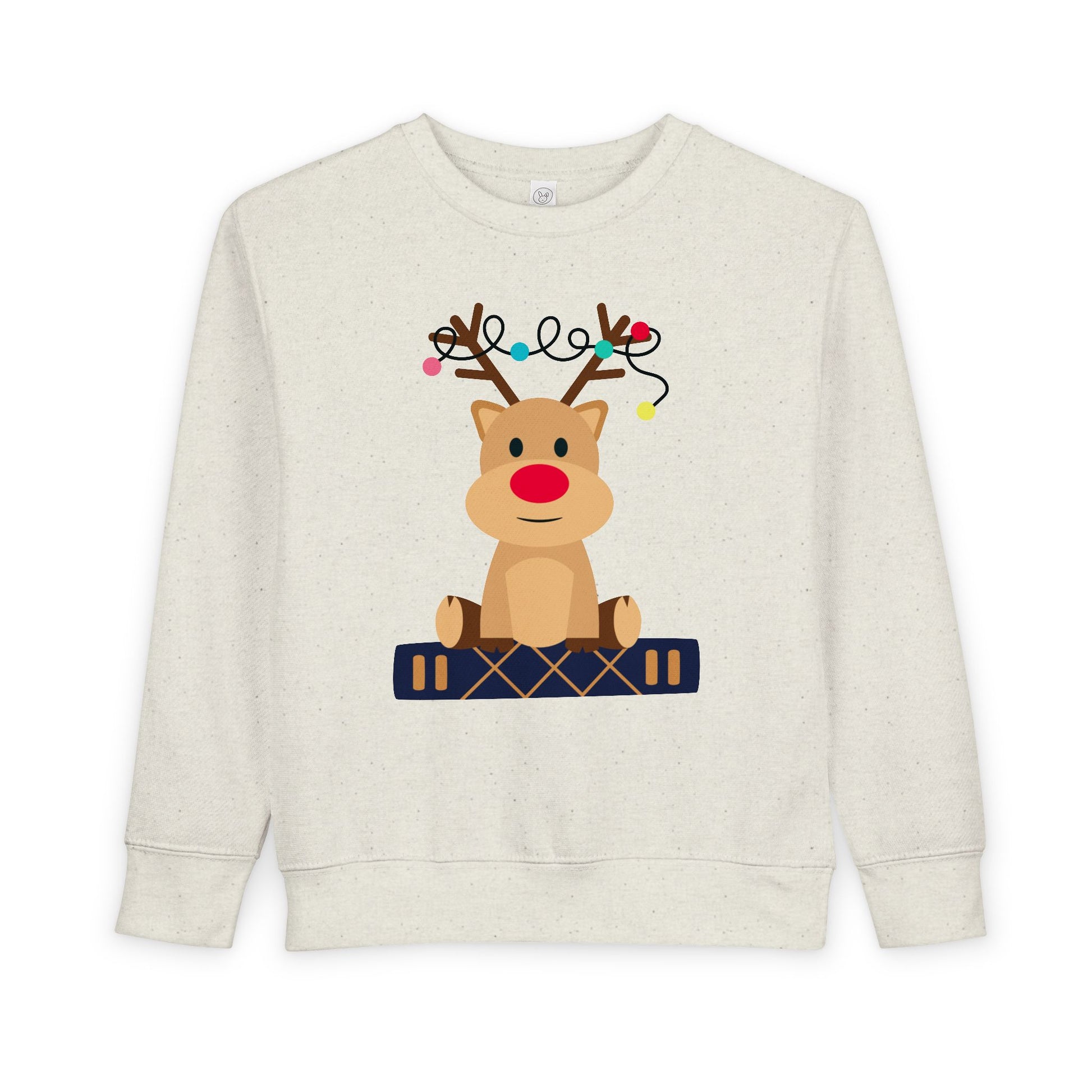 Beige toddler sweatshirt with a reindeer sitting on a book against a white background