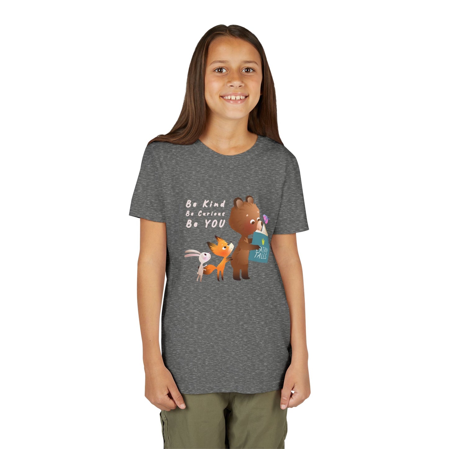 Girl wearing a gray t-shirt with cartoon animals reading a fairy tales book and text 'Be Kind. Be Curious. Be YOU.'