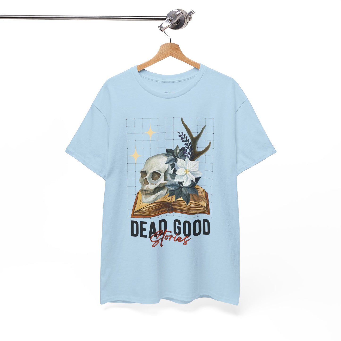 Blue t-shirt with skull, antler, and flower on a book with text 'Dead Good Stories' on a hanger against a white background