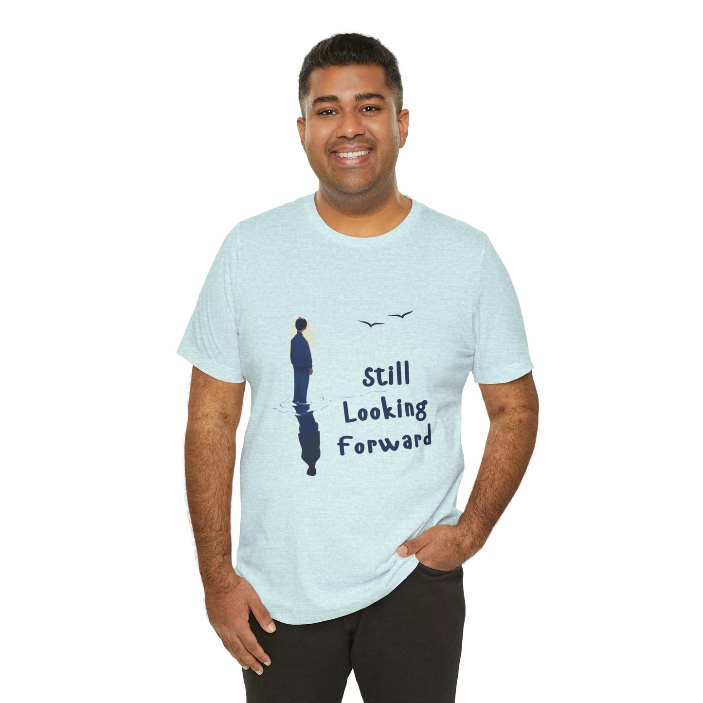 Man wearing an ice blue t-shirt with graphic of a person standing in the water with his reflection and text 'Still Looking Forward' 