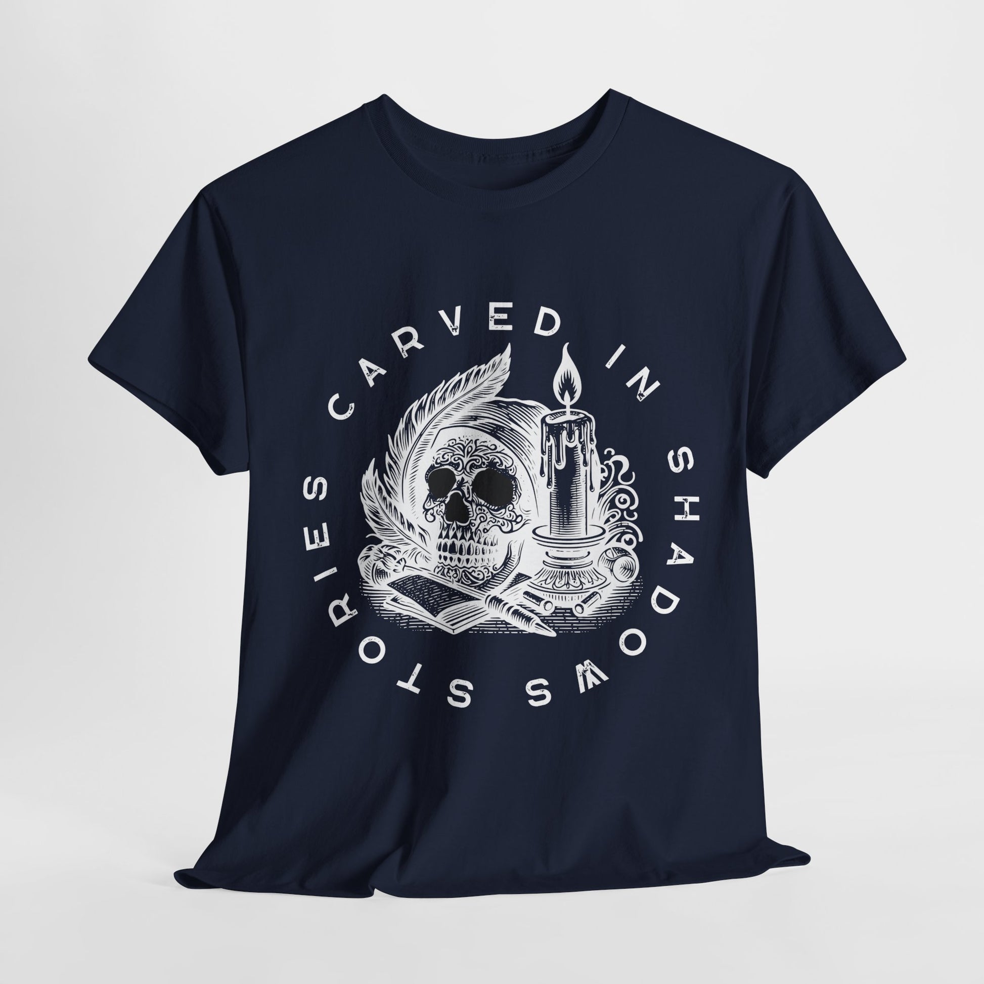 Navy blue t-shirt with white graphic skull, pen, paper, candle design, encircled with the text 'Stories Carved in Shadows'