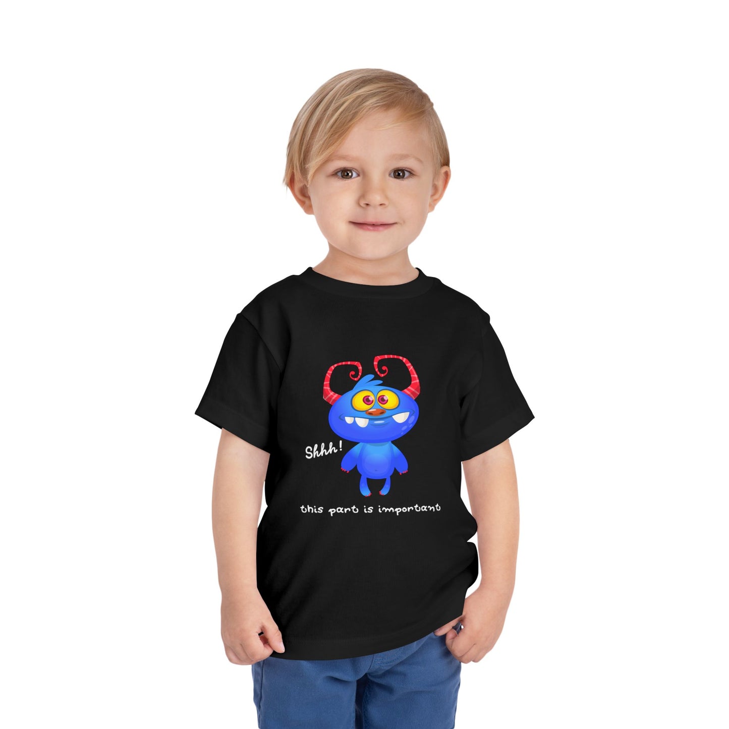 Child wearing a black toddler t-shirt with a blue monster and text 'shhh! this part is important'