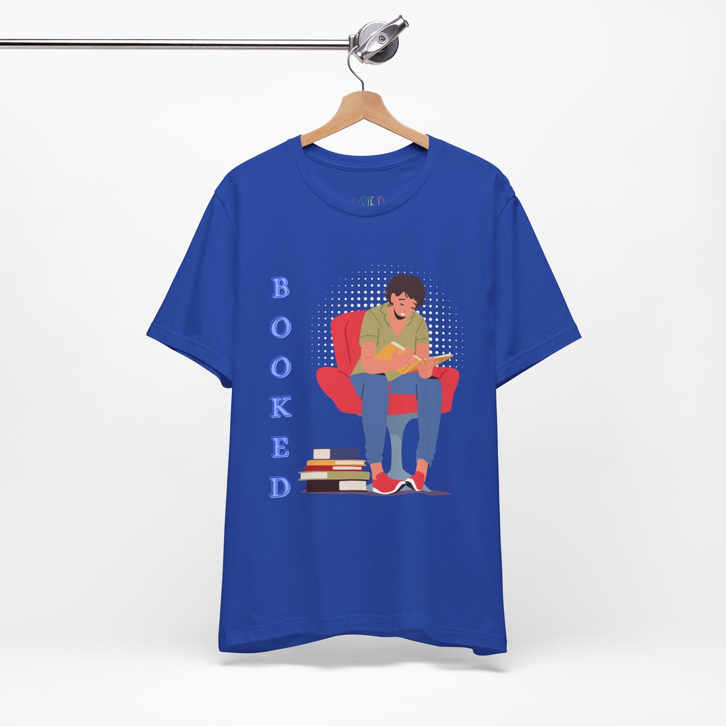 Blue t-shirt with a graphic of a person sitting in a chair, reading a book, a stack of books at his feet and text 'BOOKED' 