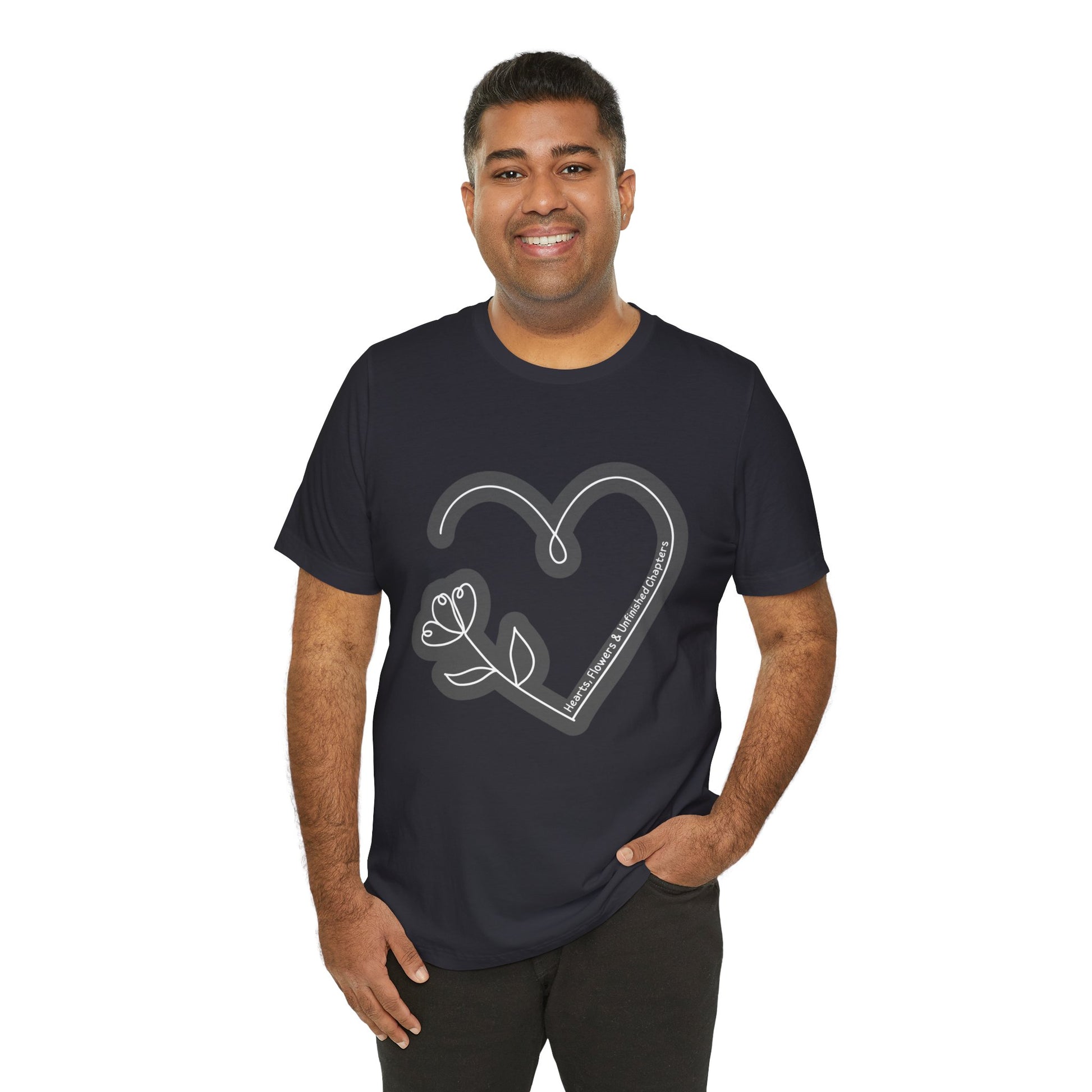 Man waring a dark grey t-shirt with a gray heart and flower sketched design and text 'Hearts, Flowers & Unfinished Chapters'